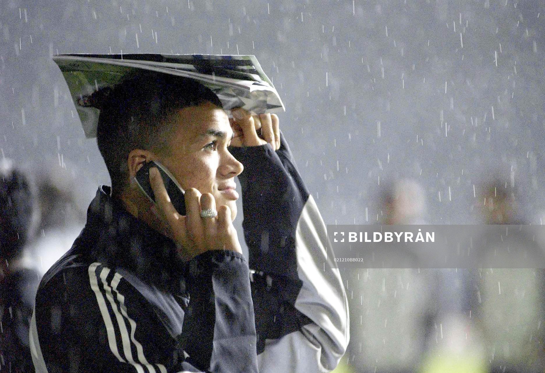  Matchen blir inställd på grund av för mycket regn. Newcastle's Jermain Jenas skyddar sig mot regnet medan han ringer med mobilen...