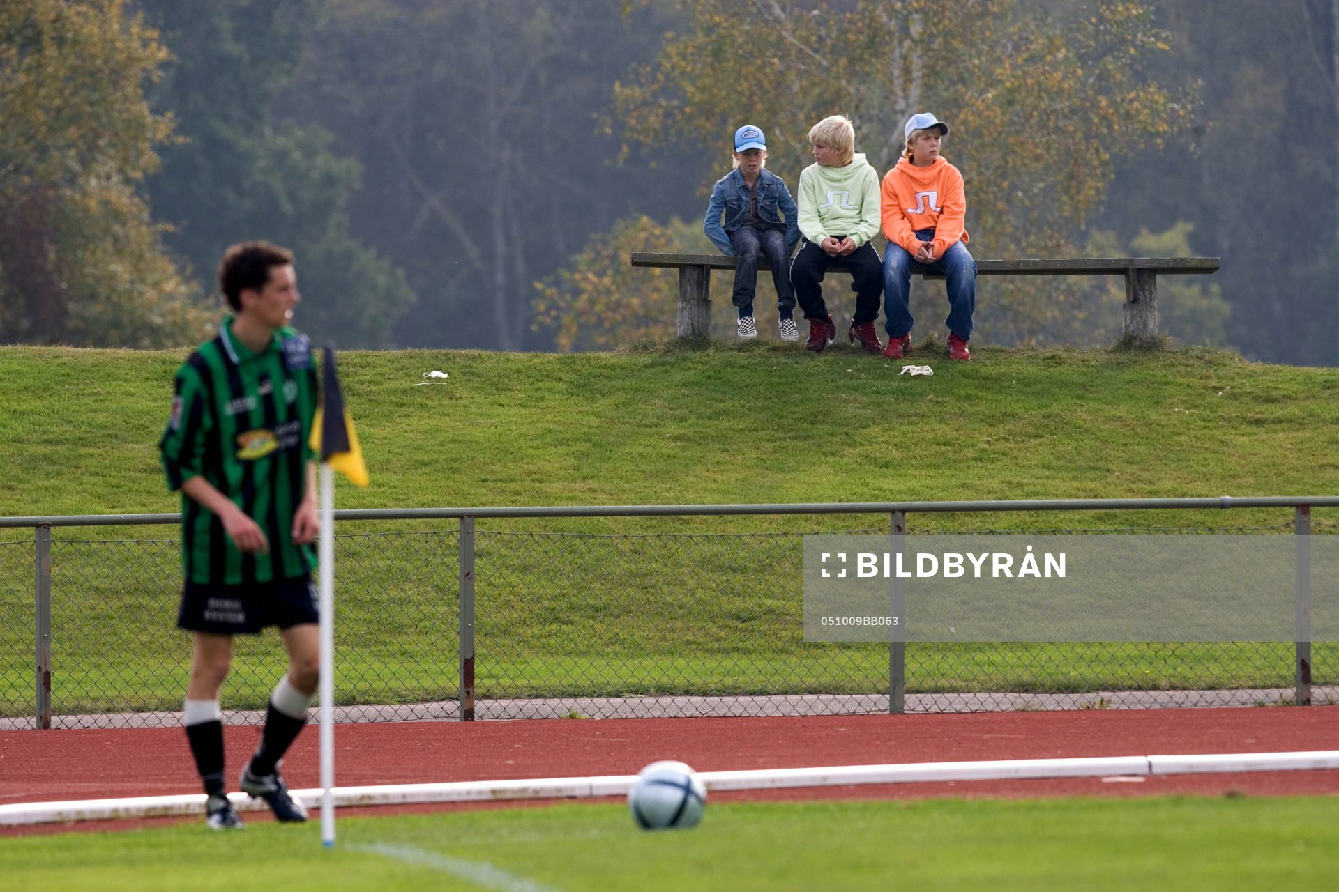 Tre unga supportrar. Bänk. Idyllisk idrottsplats