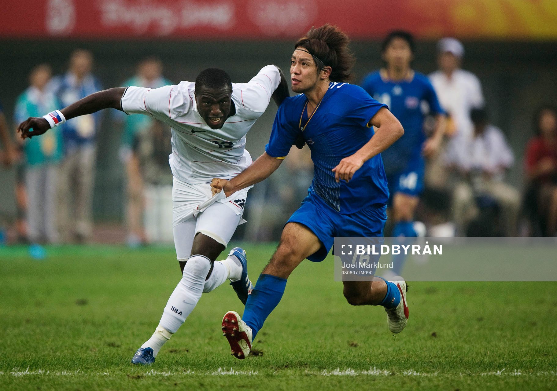  Takuya Honda, Japan, drar i tröjan på Jozy Altidore, USA.