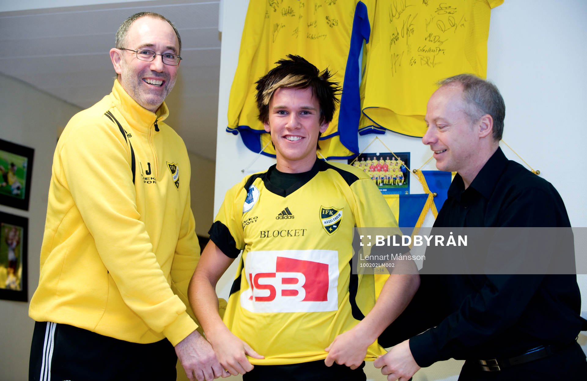  André Bengtsson, 16 år, IFK Hässleholm: Affe Jönsson, tränare, och Michael Engel, värvningsansvarig, hjälper André att ta på IFK-tröjan.