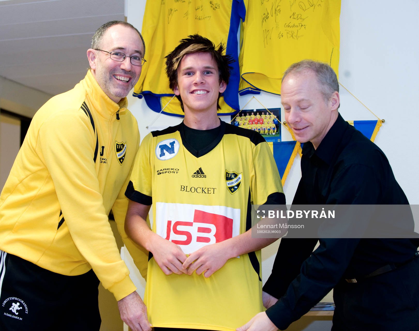 André Bengtsson, 16 år, IFK Hässleholm: Affe Jönsson, tränare, och Michael Engel, värvningsansvarig, hjälper André att ta på IFK-tröjan.