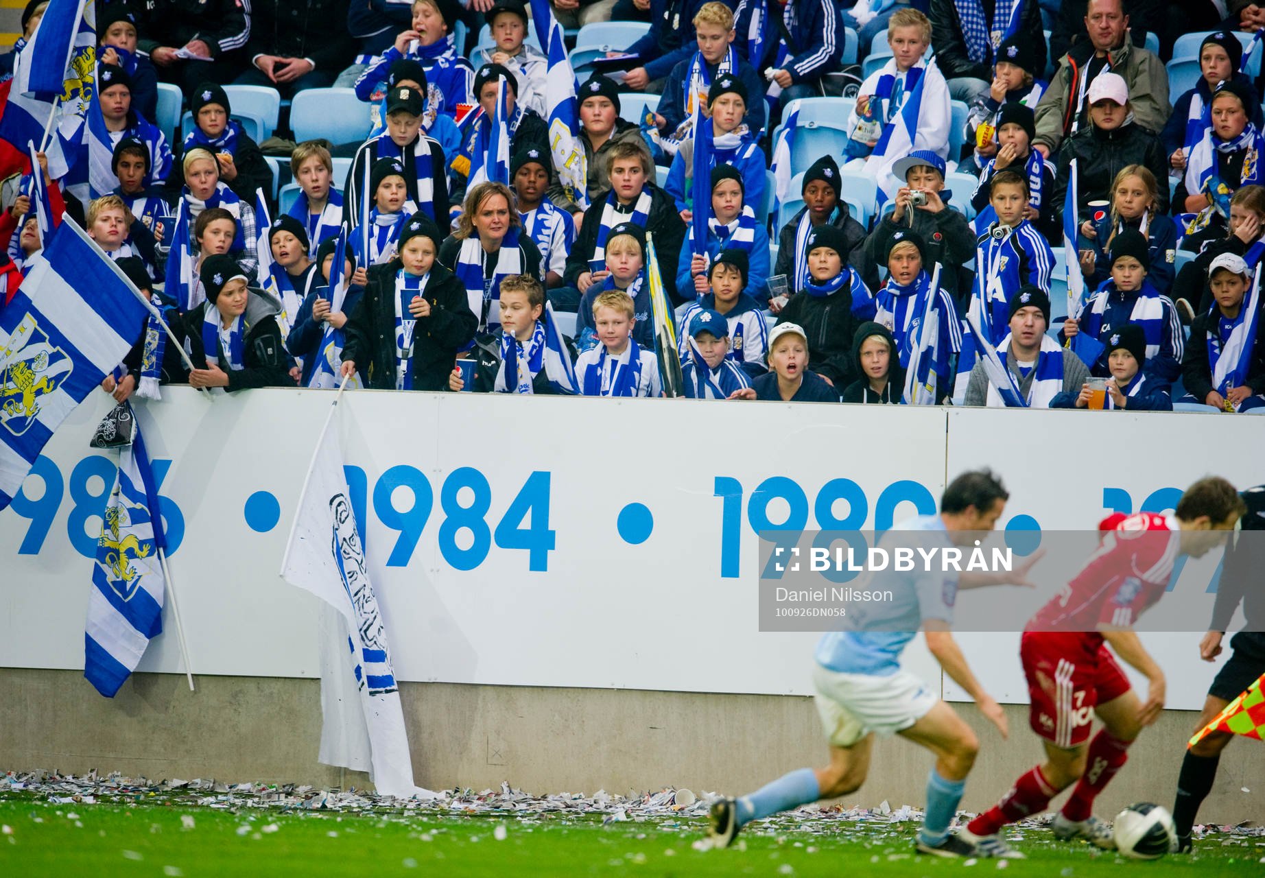 Young fellows på läktaren och utanför med flaggor