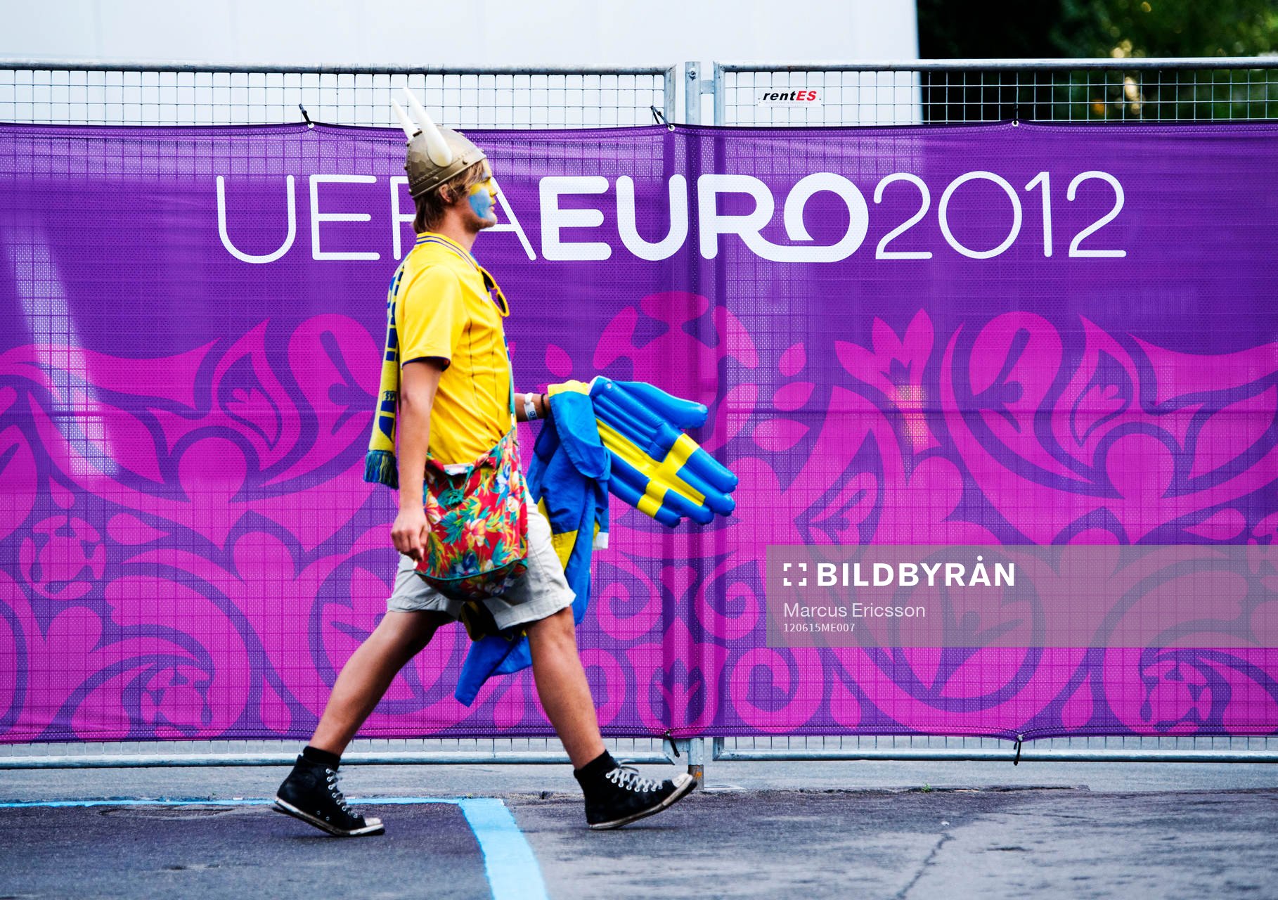 Ett svenskt fan, supporter passerar en UEFA Euro 2012-skylt