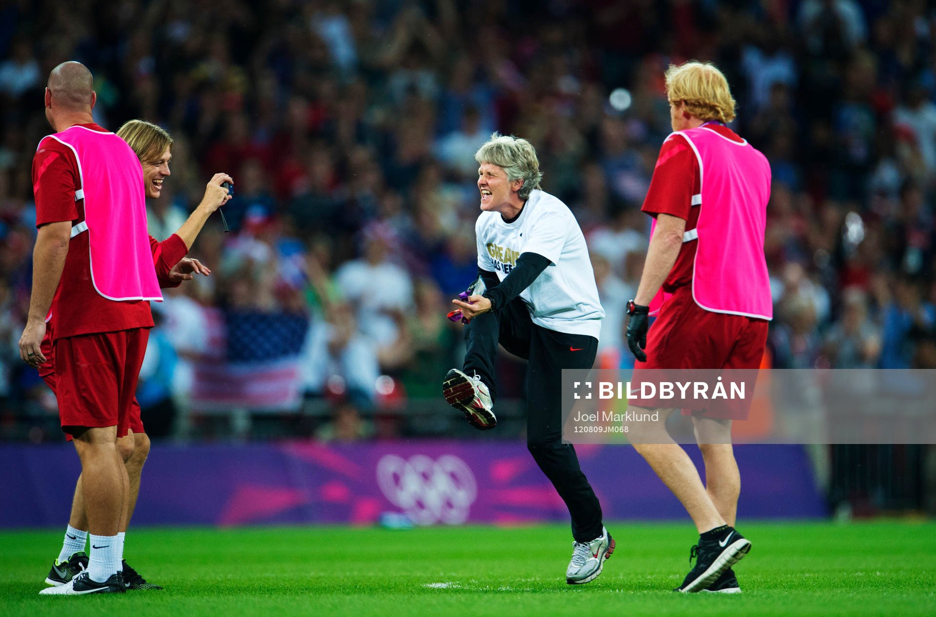 OS 2012, Fotboll, dam, final, USA - Japan: Tony Gustavsson, assisterande tränare, fotograferar Pia Sundhage, tränare, USA, som dansar på planen.