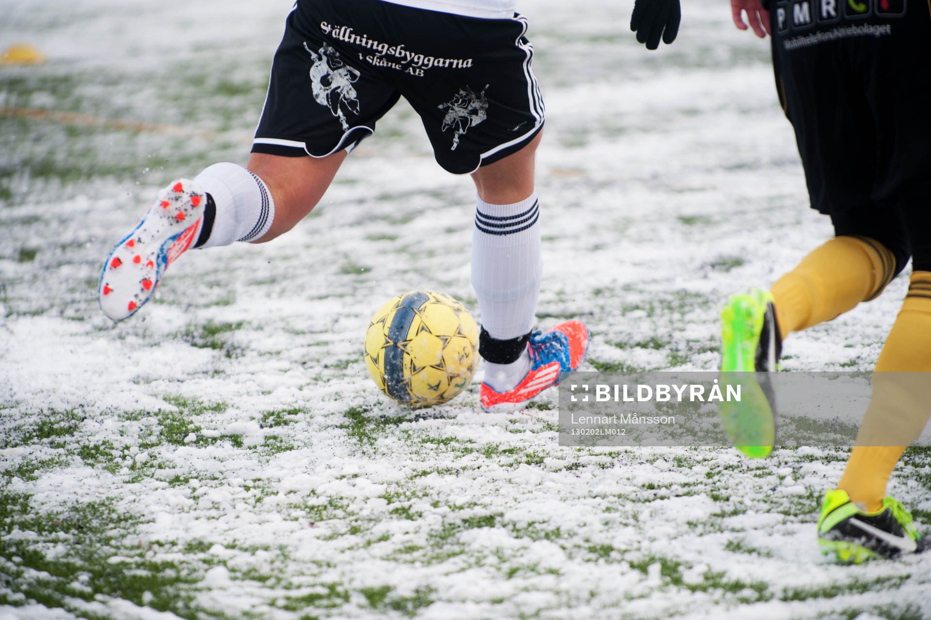 Fot, fotboll, fotbollsskor. Snö, snöig konstgräsplan.