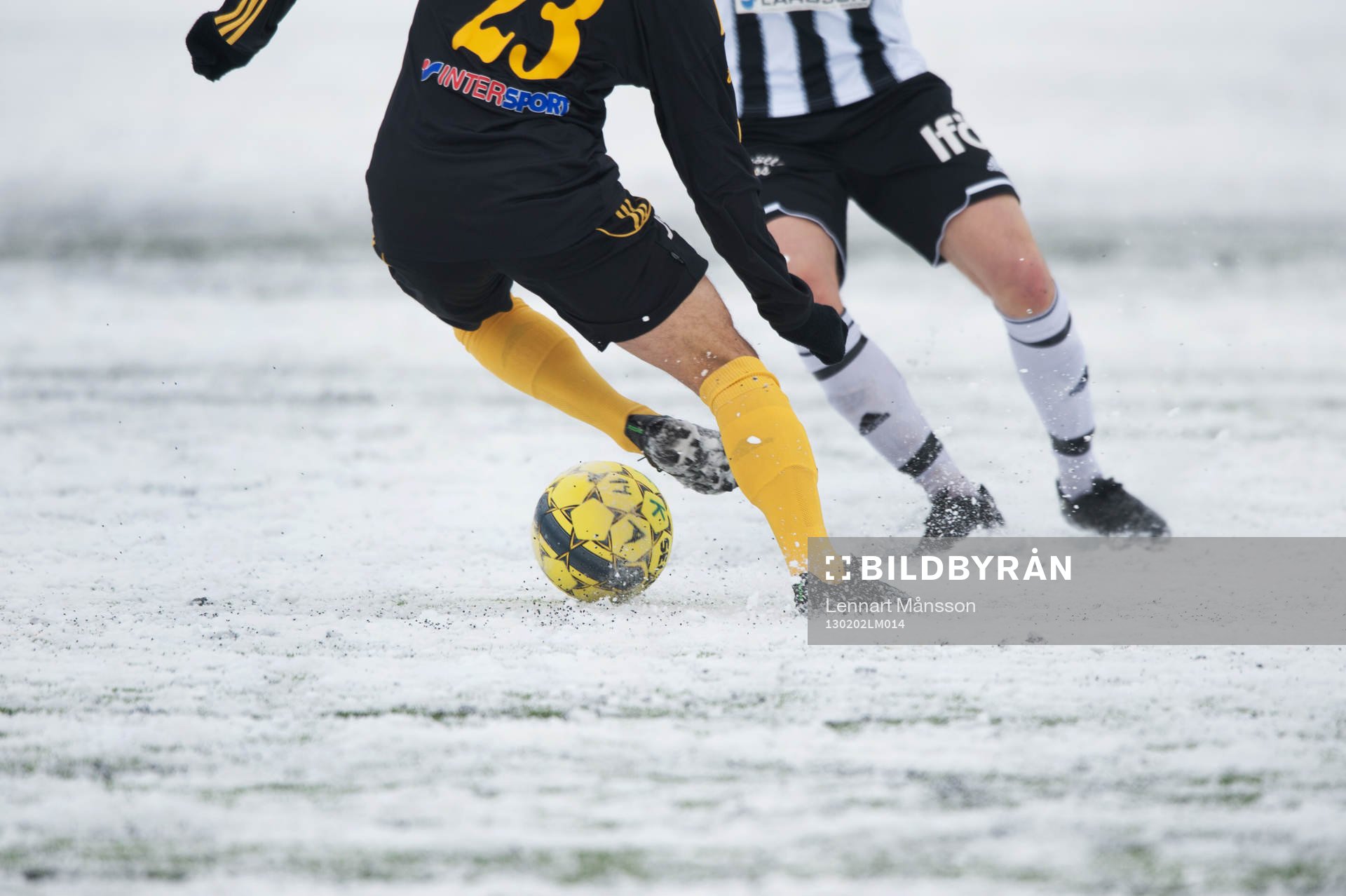 Fot, fotboll, fotbollsskor. Snö, snöig konstgräsplan.