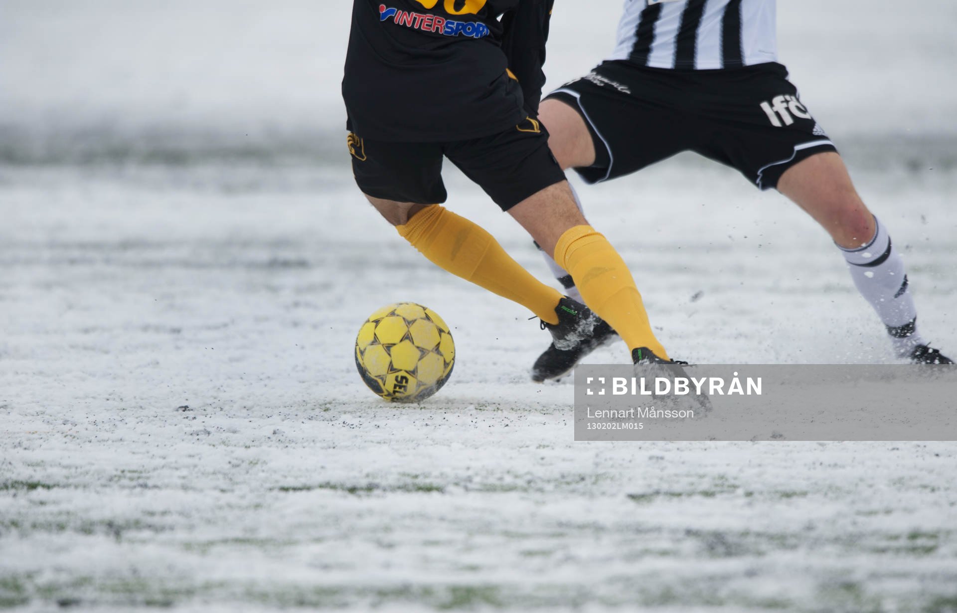 Fot, fotboll, fotbollsskor. Snö, snöig konstgräsplan.