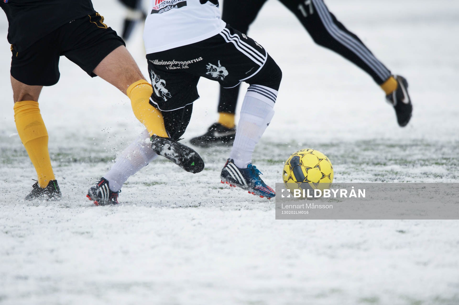 Fot, fotboll, fotbollsskor. Snö, snöig konstgräsplan.