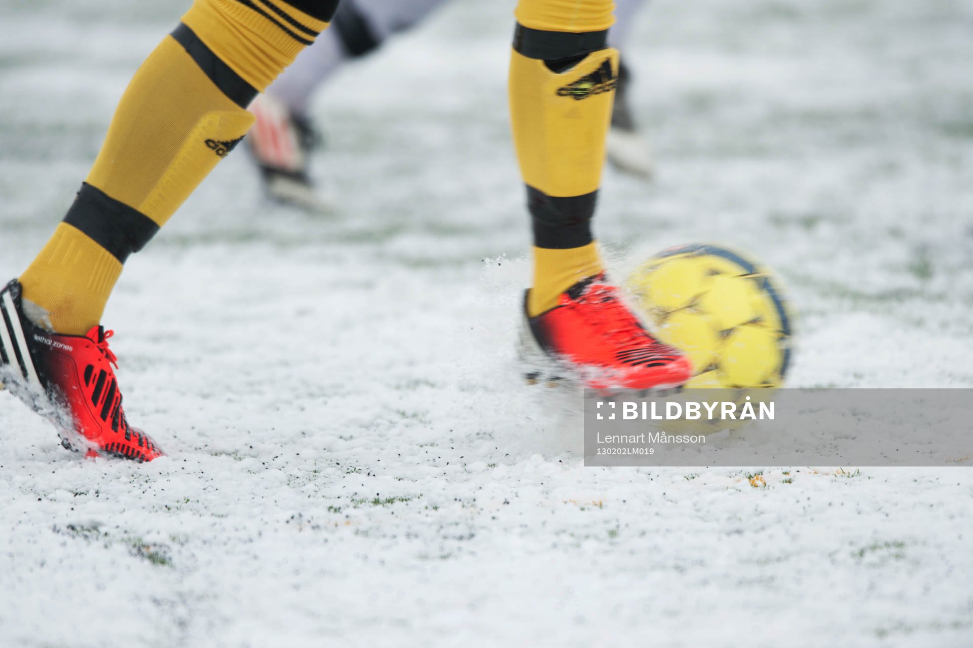Fot, fotboll, fotbollsskor. Snö, snöig konstgräsplan.