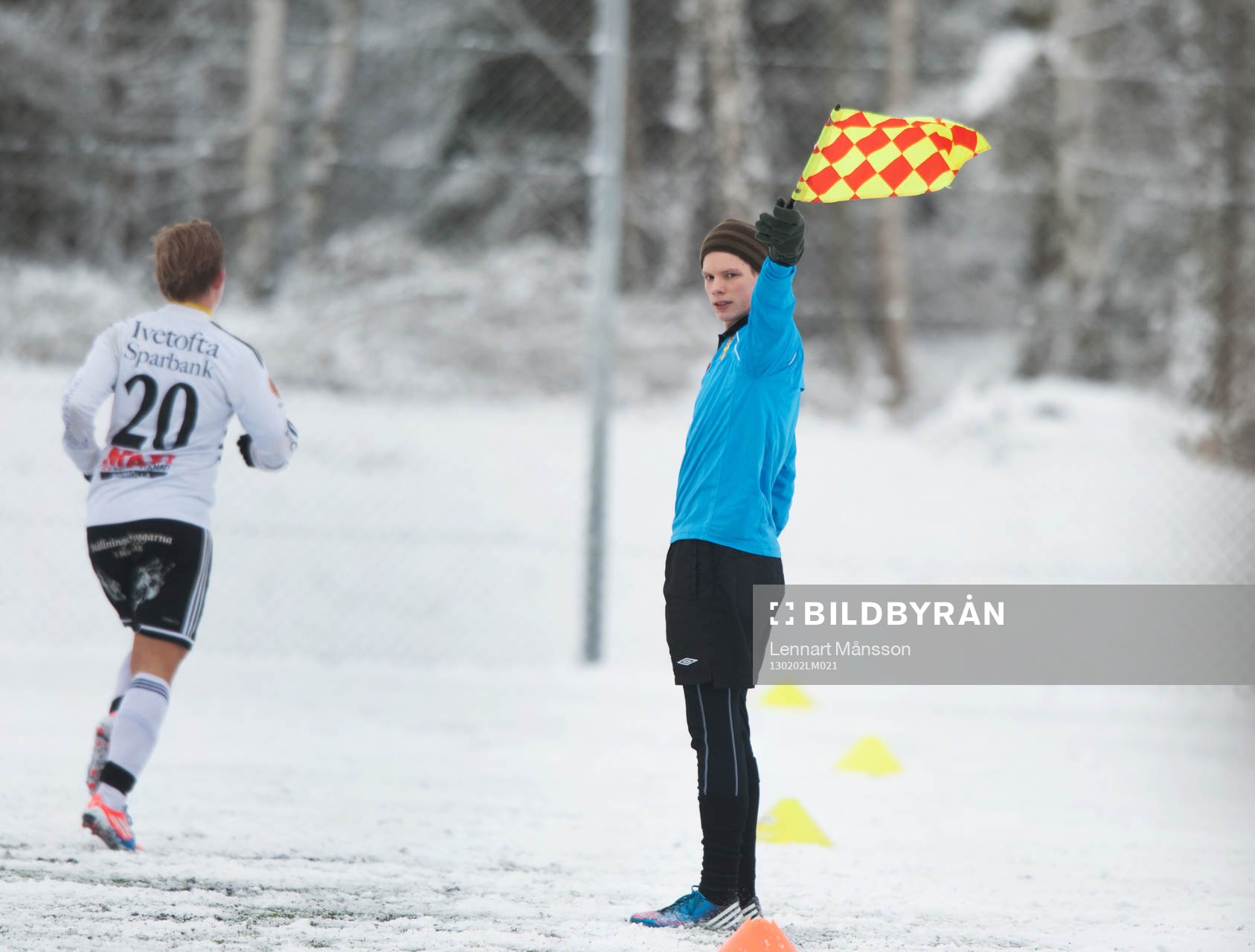 Assisterande domare, flagga. Snö, snöig konstgräsplan.