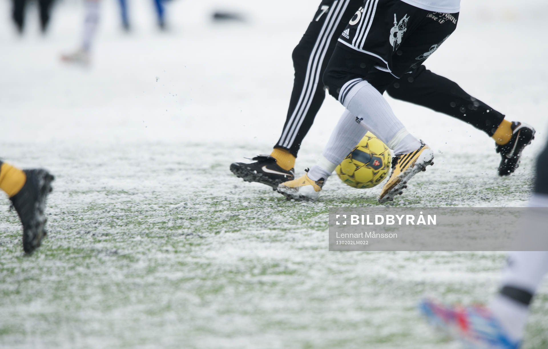 Fot, fotboll, fotbollsskor. Snö, snöig konstgräsplan.