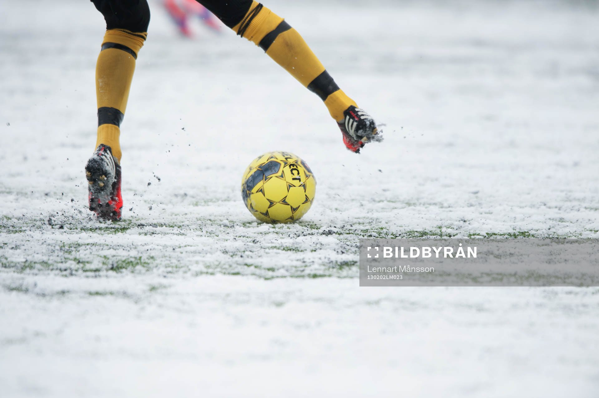 Fot, fotboll, fotbollsskor. Snö, snöig konstgräsplan.