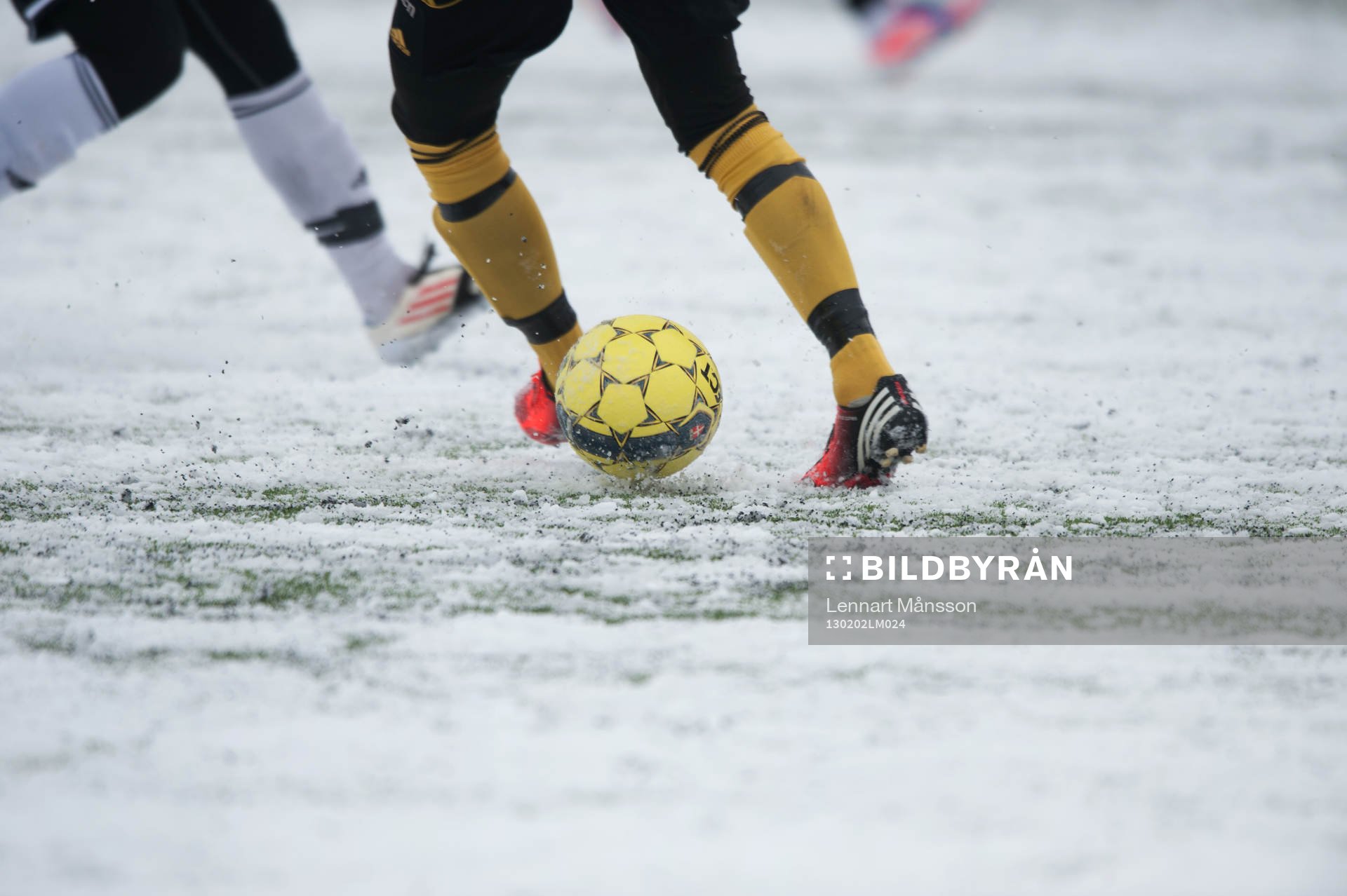 Fot, fotboll, fotbollsskor. Snö, snöig konstgräsplan.