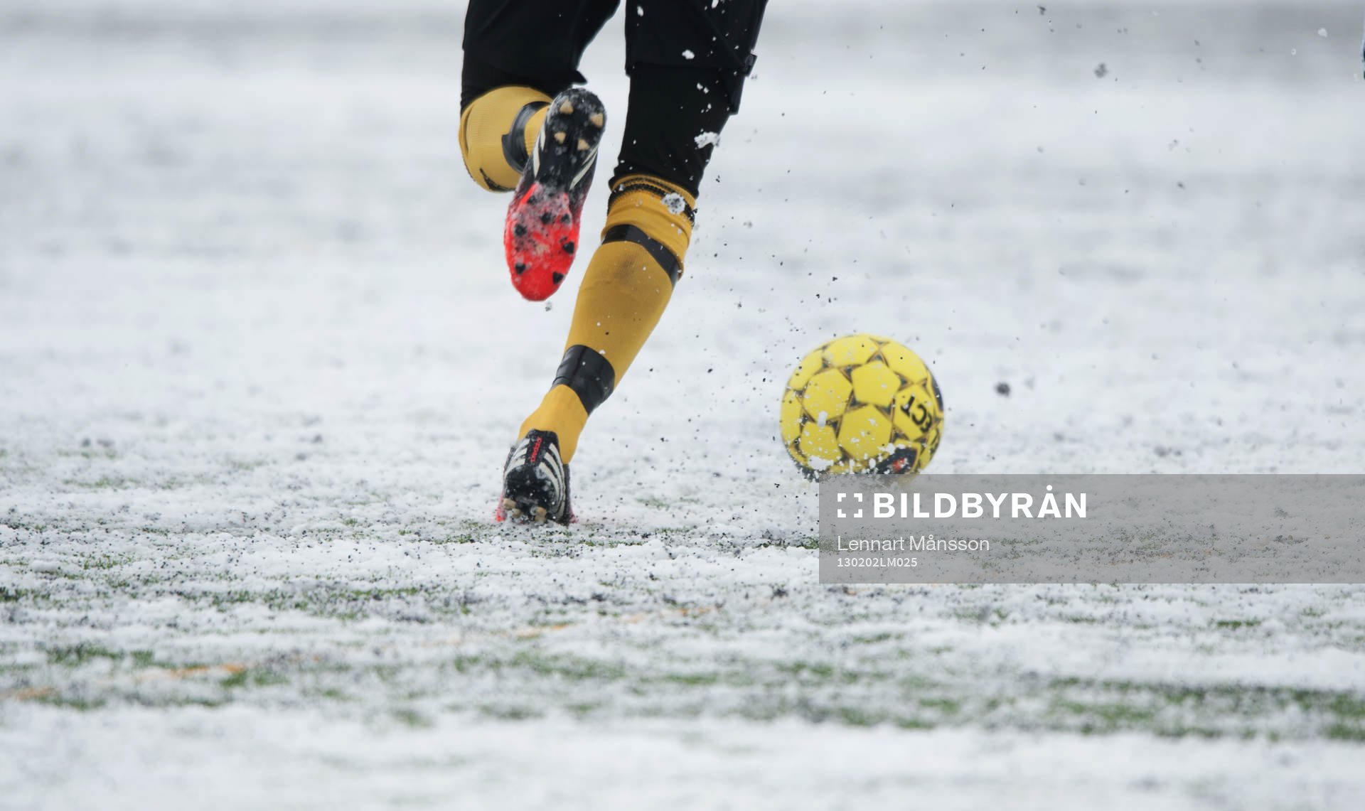 Fot, fotboll, fotbollsskor. Snö, snöig konstgräsplan.