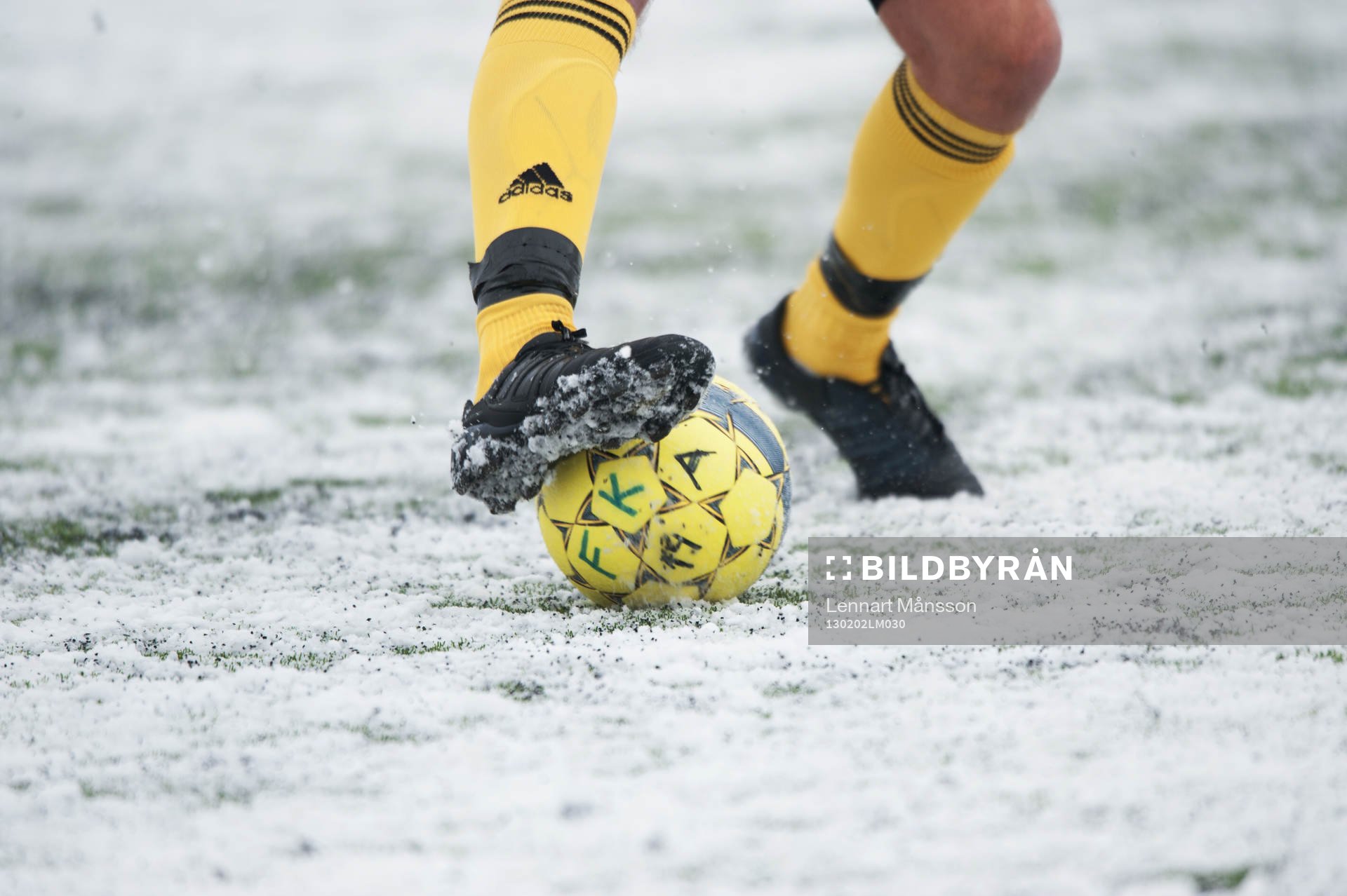 Fot, fotboll, fotbollsskor. Snö, snöig konstgräsplan.
