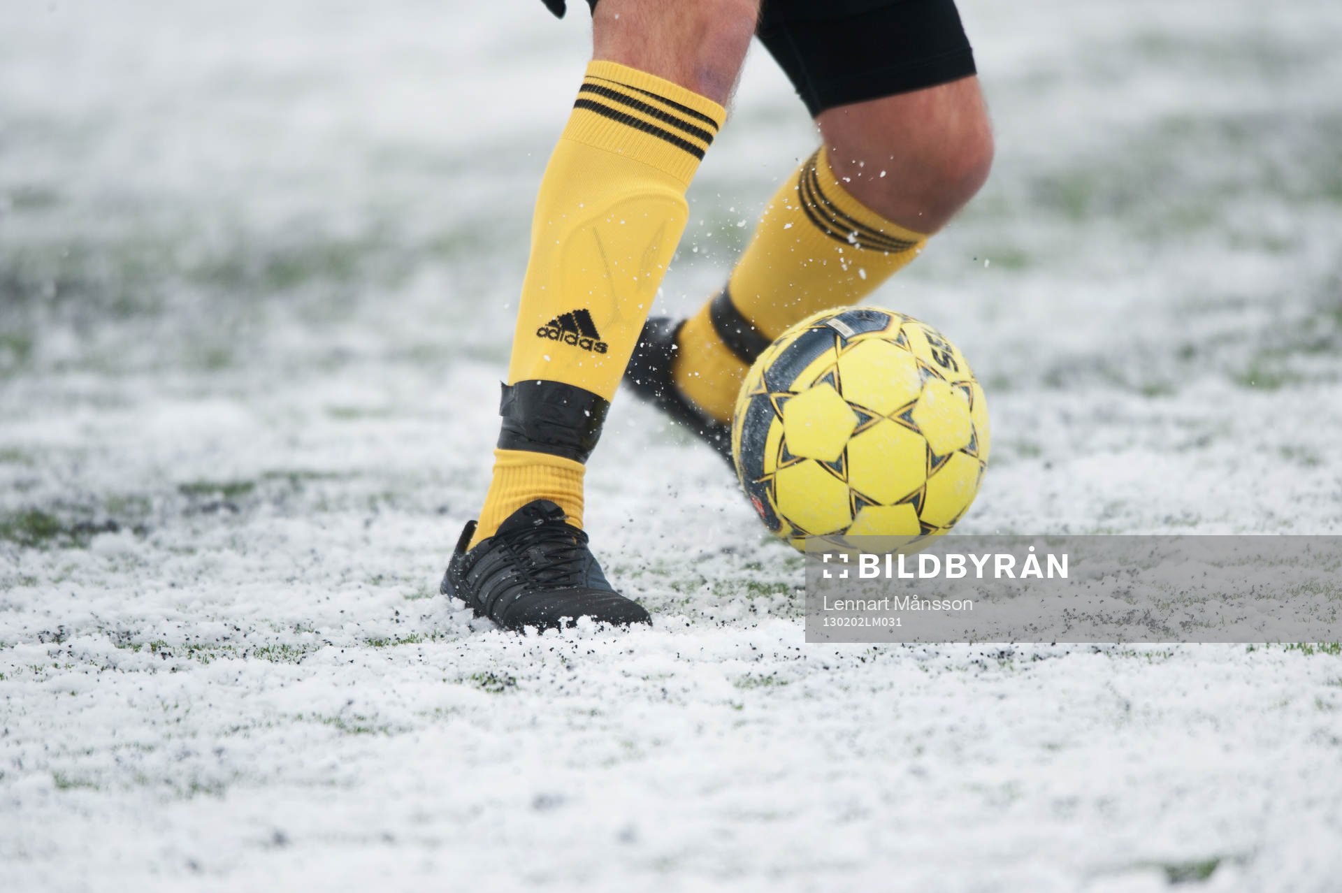 Fot, fotboll, fotbollsskor. Snö, snöig konstgräsplan.