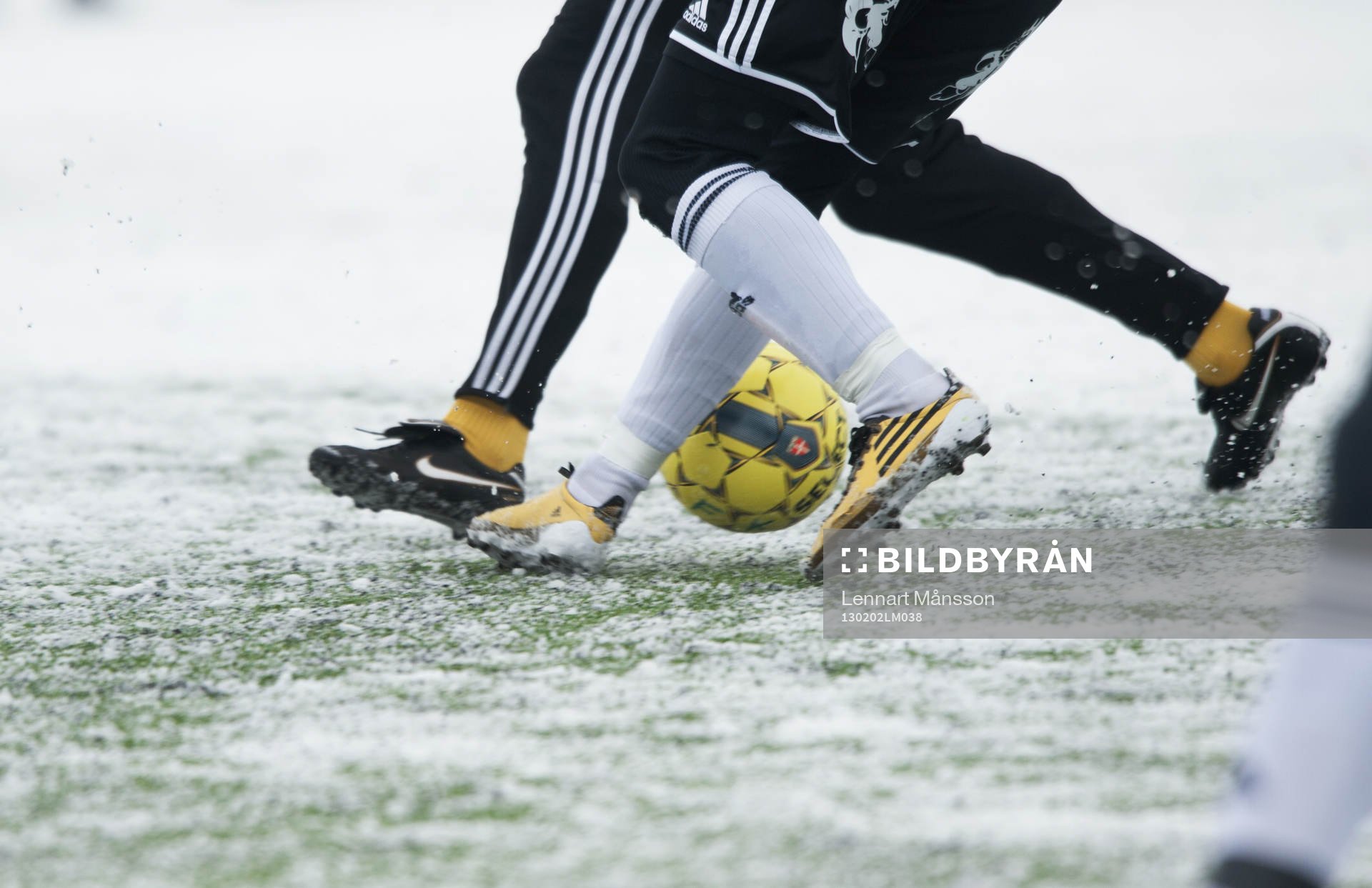 Fot, fotboll, fotbollsskor. Snö, snöig konstgräsplan.