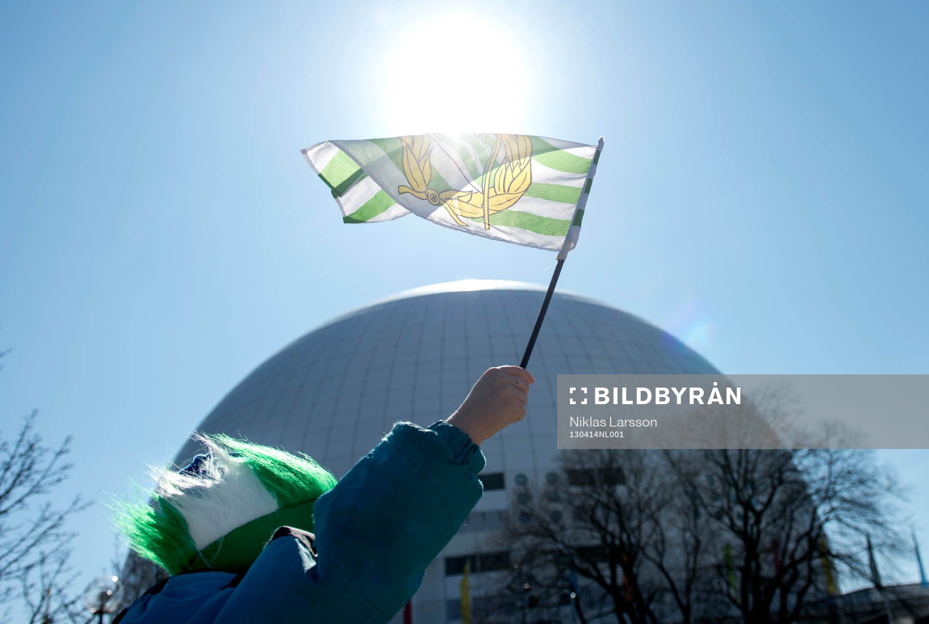En Hammarbysupporter håller upp en Hammarbyflagga framför