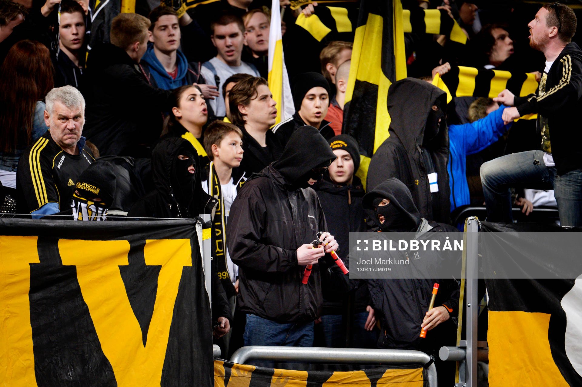 Maskerade personer i AIK-klacken med bengaler innan matchen
