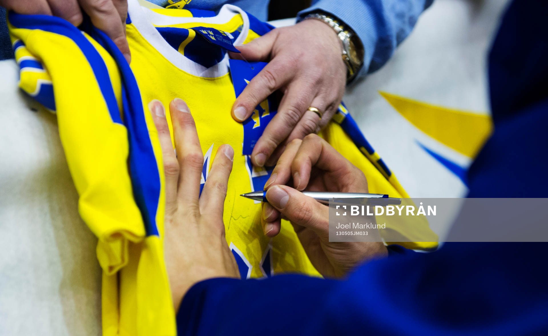 En spelare skriver sin autograf på en matchströja
