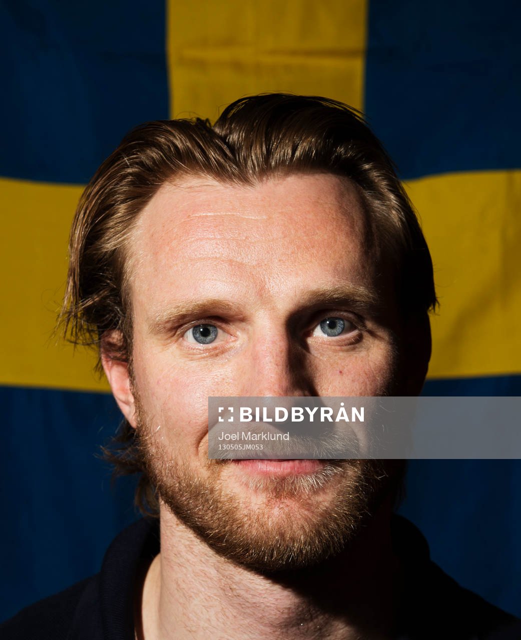 Staffan Kronwall poserar framför en svensk flagga när det