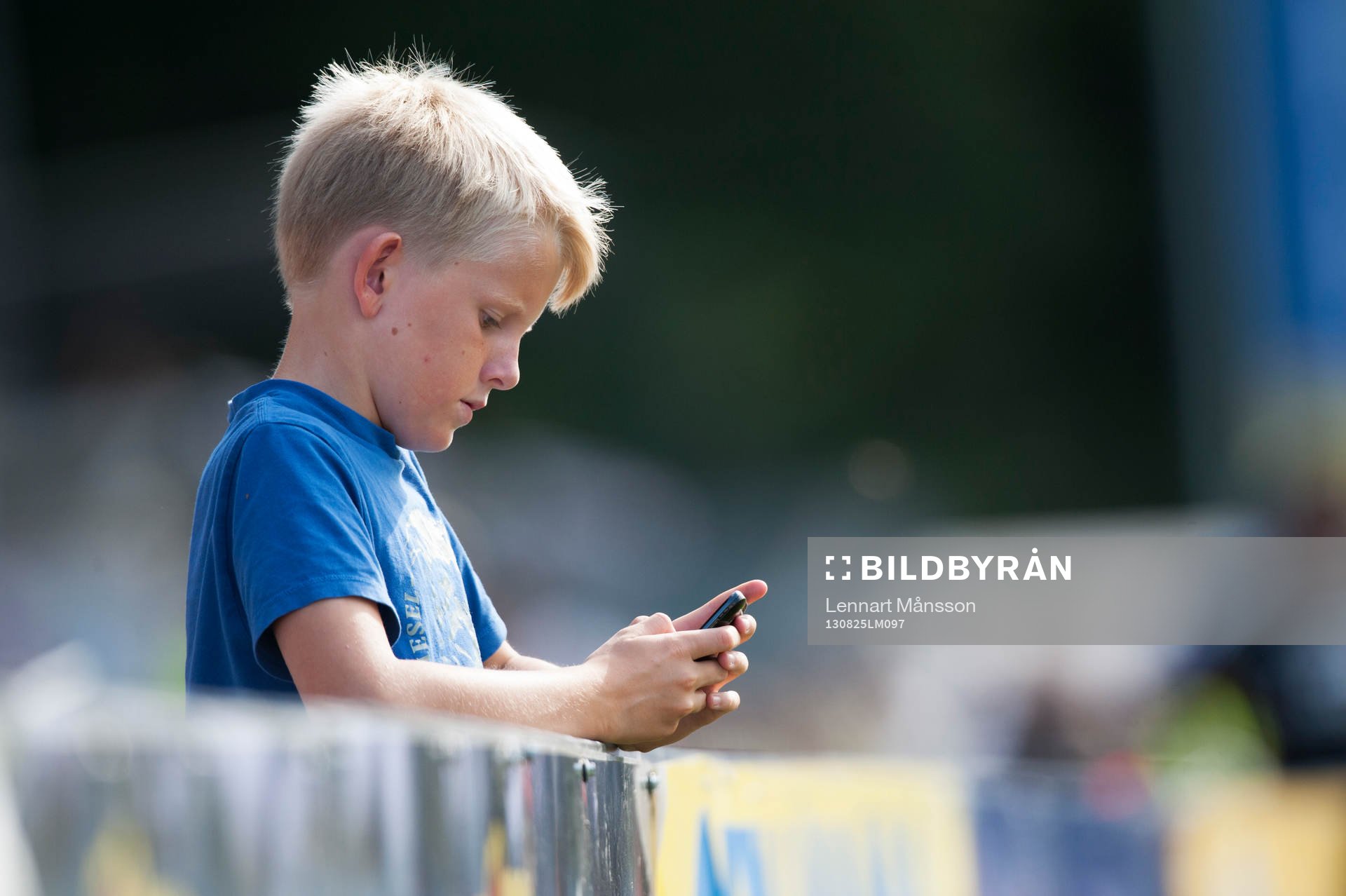 Pojke kollar mobiltelefonen mitt