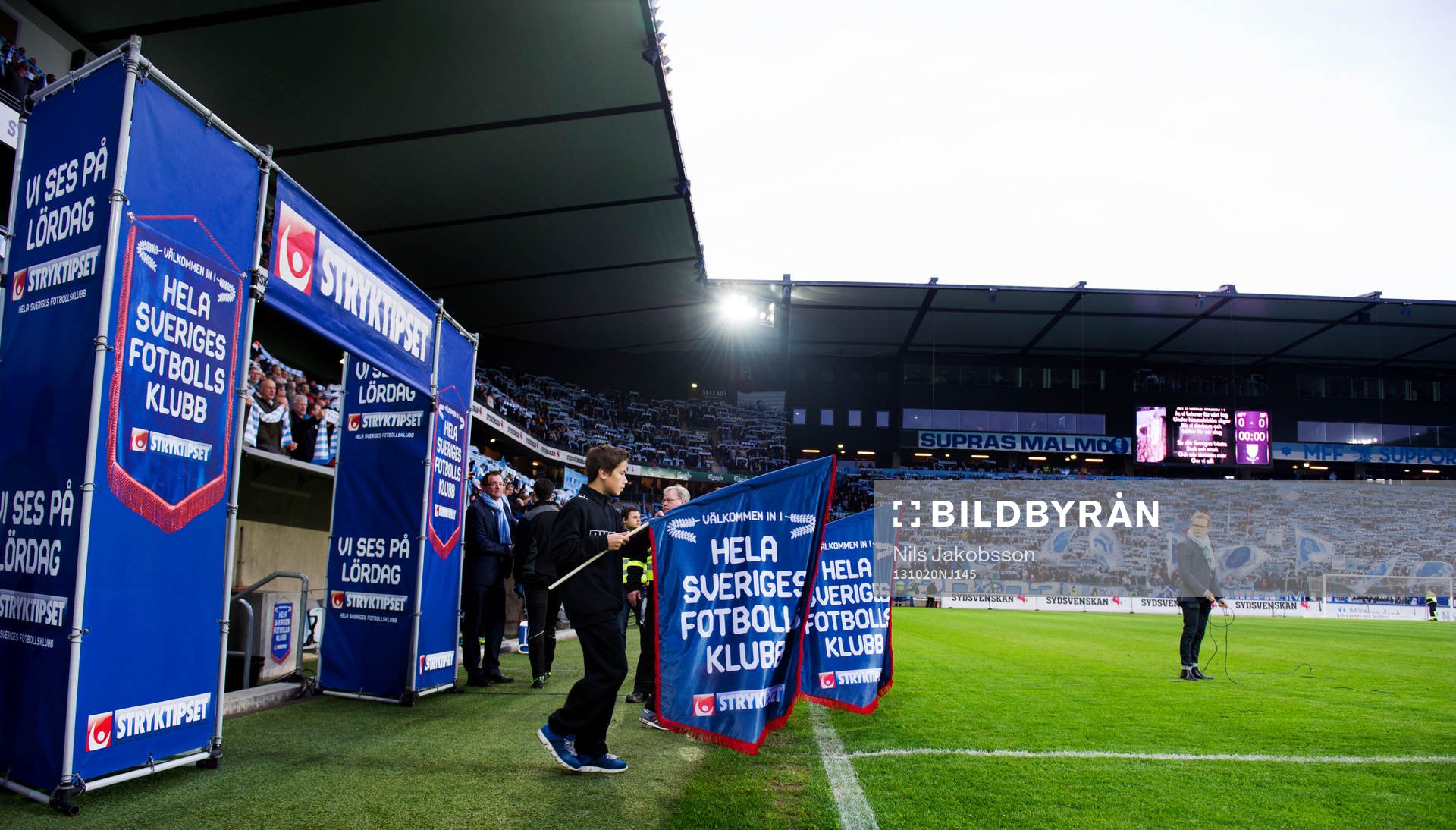 Två pojkar med flaggor gör entre innan fotbollsmatchen i