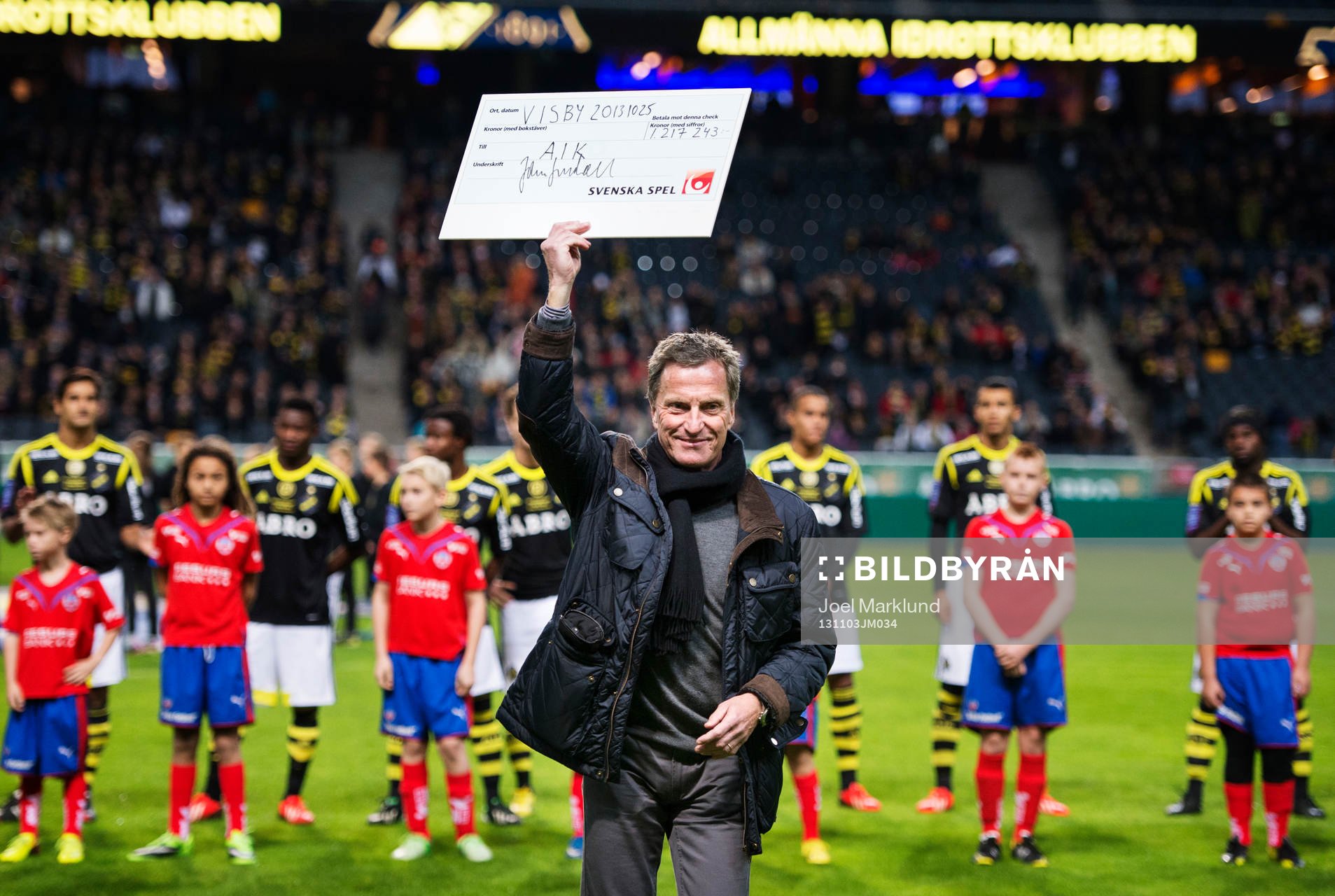 En representant från AIK håller upp en check från