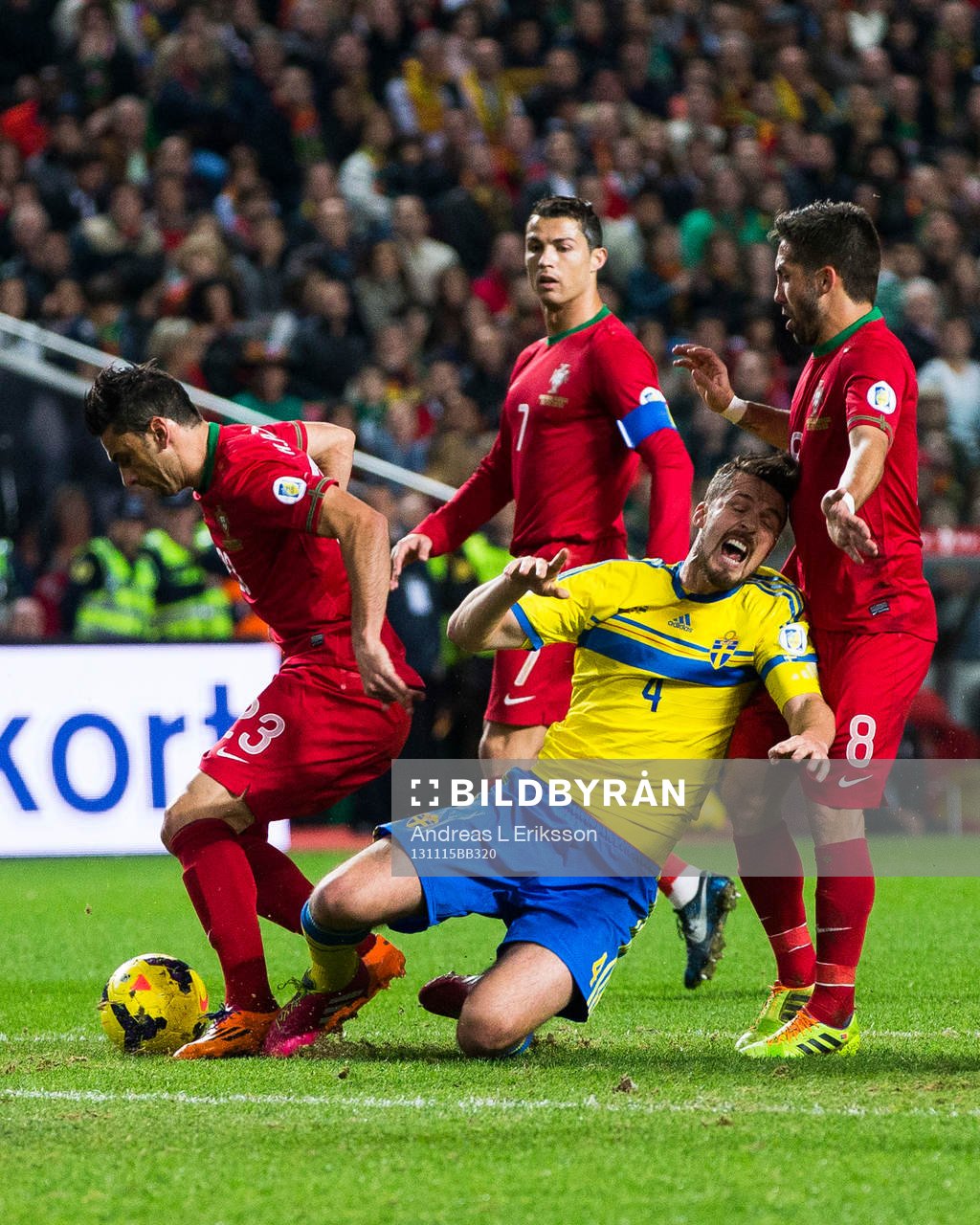Sveriges Per Nilsson går omkull i en närkamp med Portugals Hélder Postiga, Cristiano Ronaldo och Joâo Moutinho under playoff-matchen i VM-kvalet mellan Portugal och Sverige den 15 november 2013 i Lissabon.