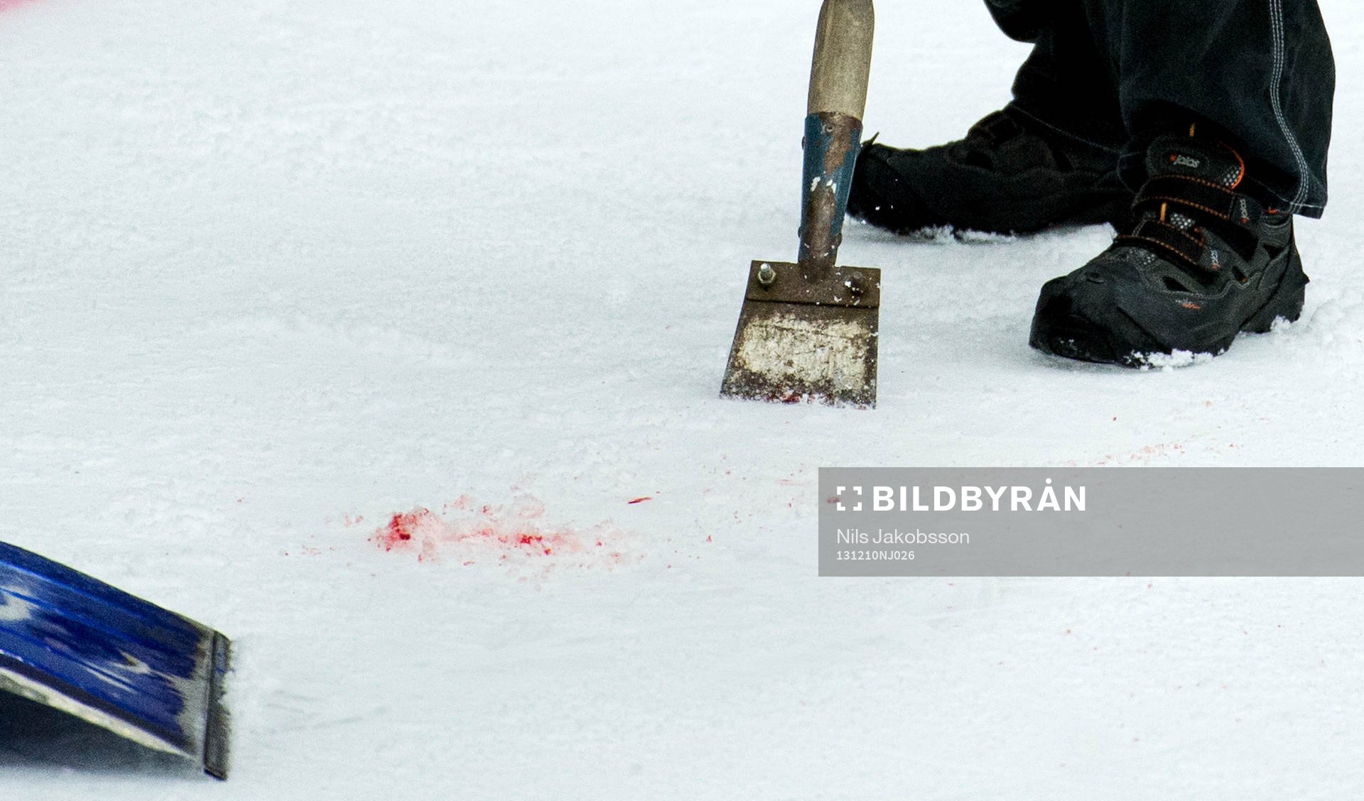 Blod på isen skrapas bort av vaktmästaren