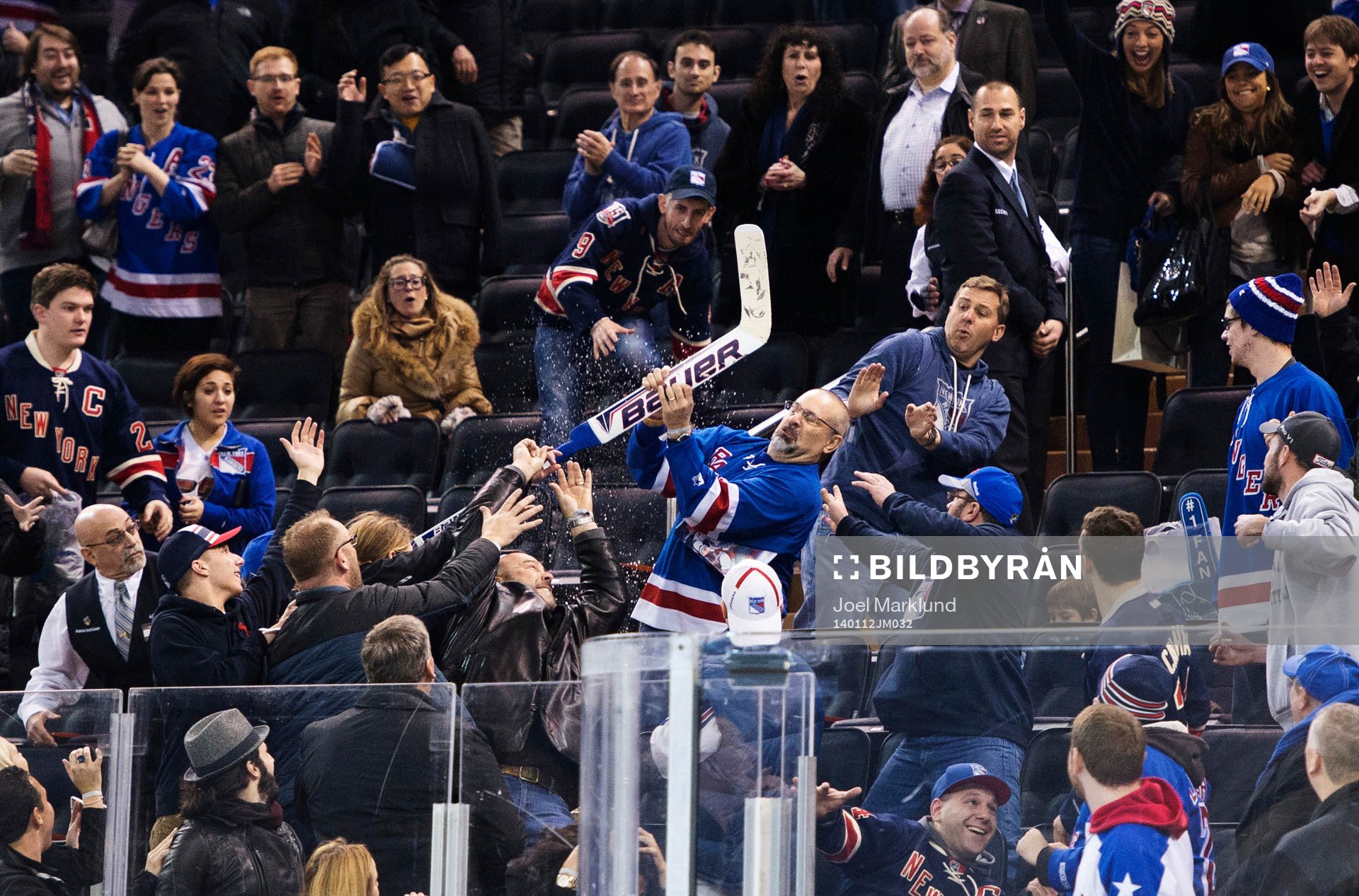 En man fångar en hockeyklubba som Henrik Lundqvist kastat