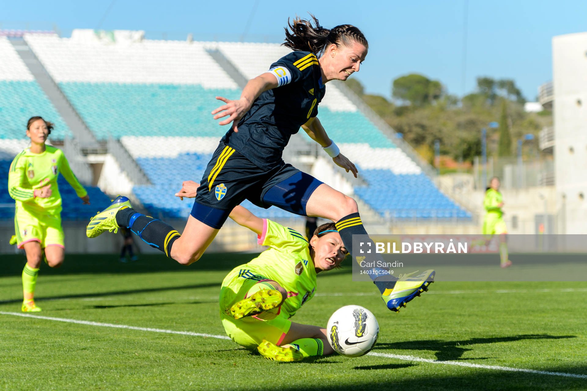 Sveriges Lotta Schelin hoppar över försvarande Japans Saki Kumagai under fotbollsmatchen mellan Japan och Sverige i Algarve Cup den 10 mars 2014.