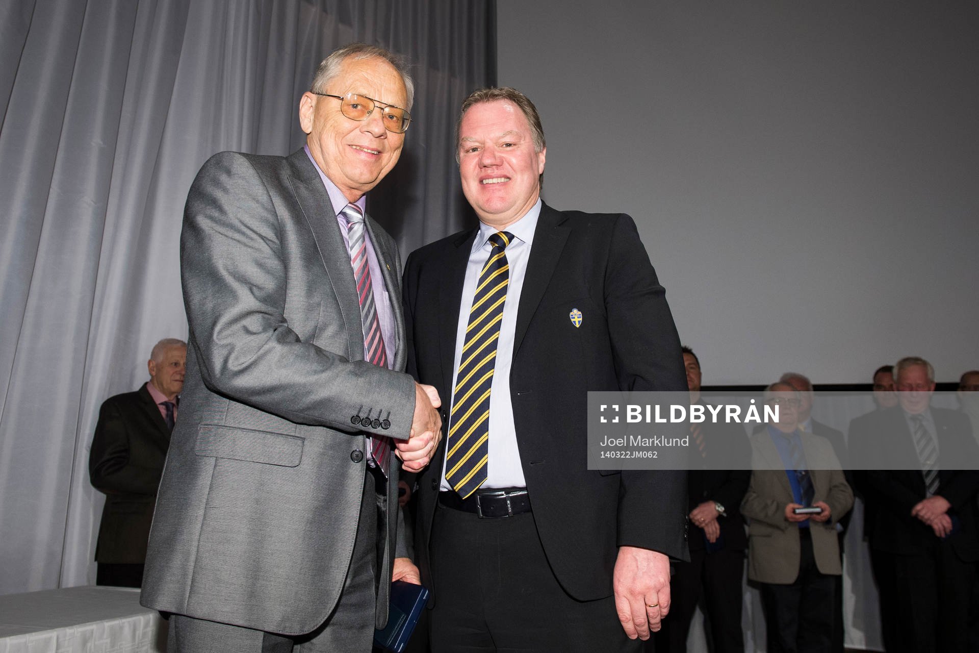 Hans Hillbom tar emot en medalj för sina insatser av Karl-Erik Nilsson, ordförande SvFF, under Svenska Fotbollförbundets årsmöte den 22 mars 2014 i Stockholm.