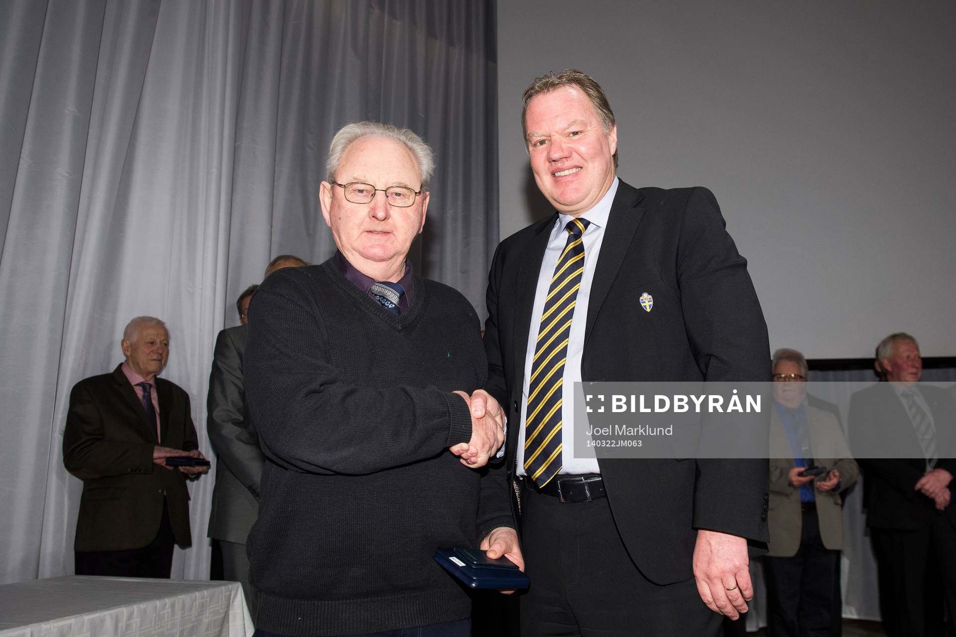 Verne Olofsson tar emot en medalj för sina insatser av Karl-Erik Nilsson, ordförande SvFF, under Svenska Fotbollförbundets årsmöte den 22 mars 2014 i Stockholm.