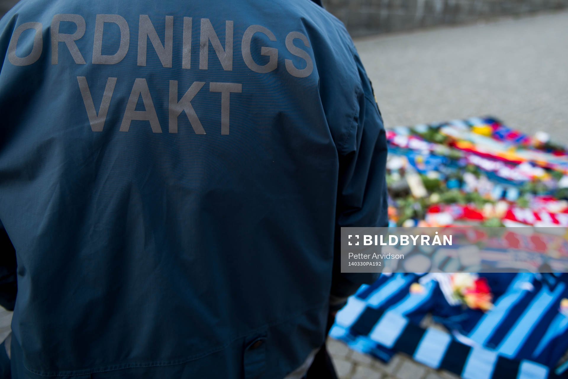 En ordningsvakt vid tända ljus och utlagda halsdukar och