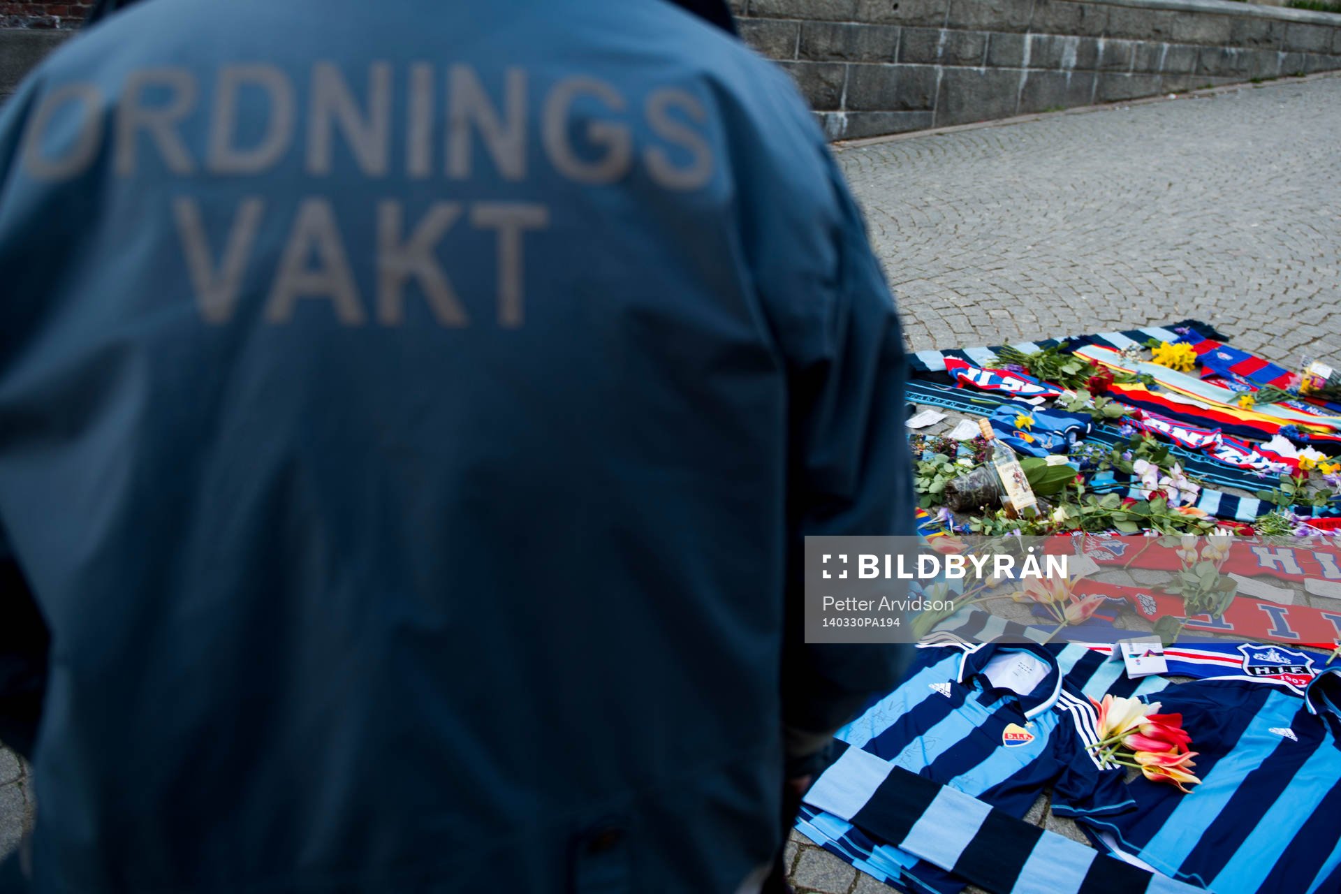 En ordningsvakt vid tända ljus och utlagda halsdukar och