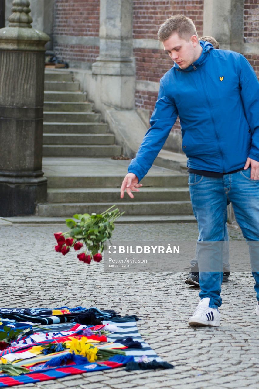 Personer sörjer vid tända ljus och utlagda halsdukar och