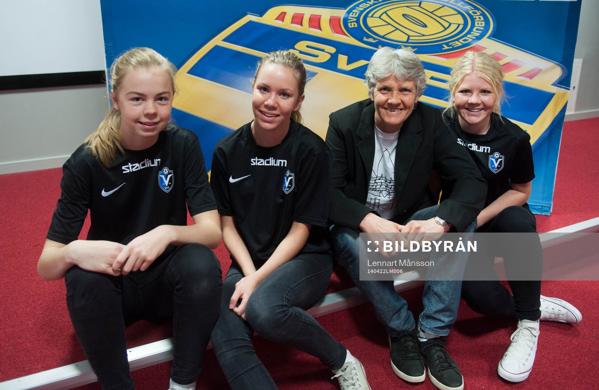 Förbundskapten Pia Sundhage med tre tjejer som är