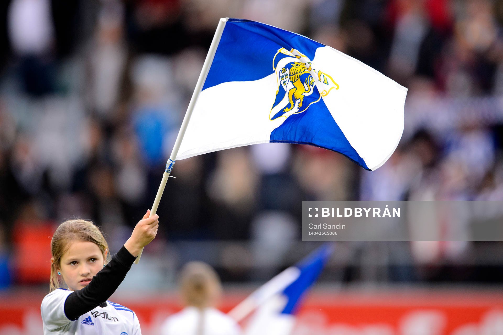 En tjej viftar med en flagga innan fotbollsmatchen i