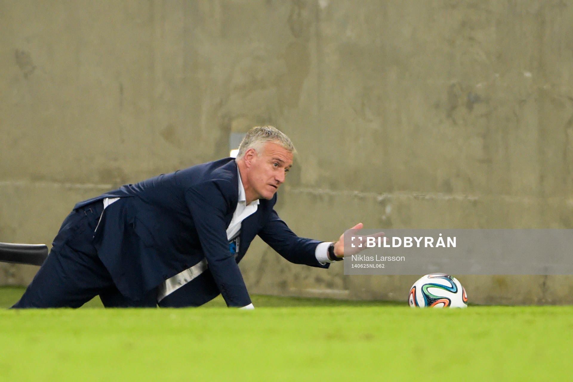 Frankrikes förbundskapten Didier Deschamps kryper på knä efter bollen under fotbollsmatchen mellan Frankrike och Ecuador under fotbolls-VM den 25 juni 2014 i Rio de Janeiro.