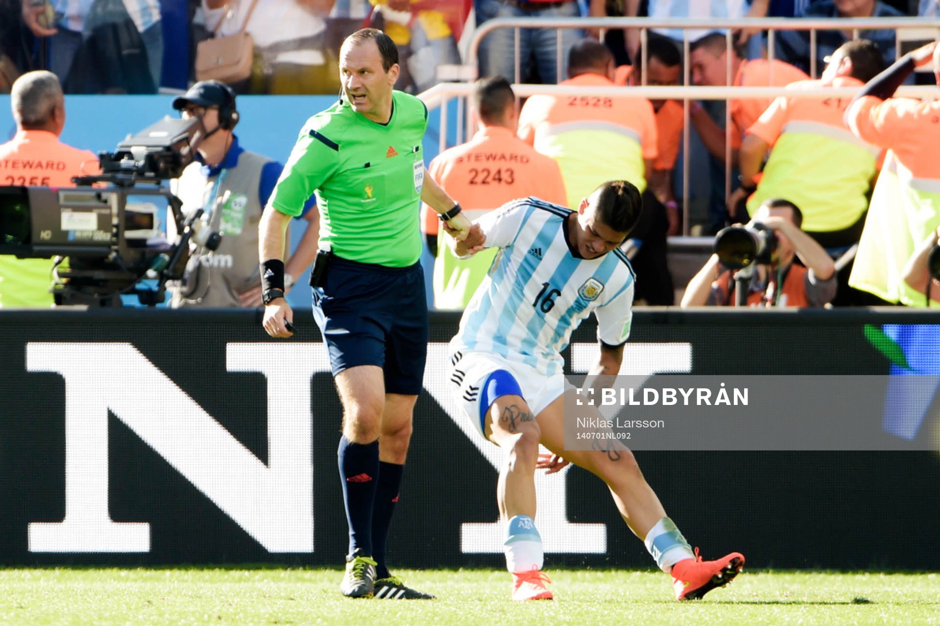 Jonas Eriksson, domare hjälper Argentinas Marcos Rojo upp