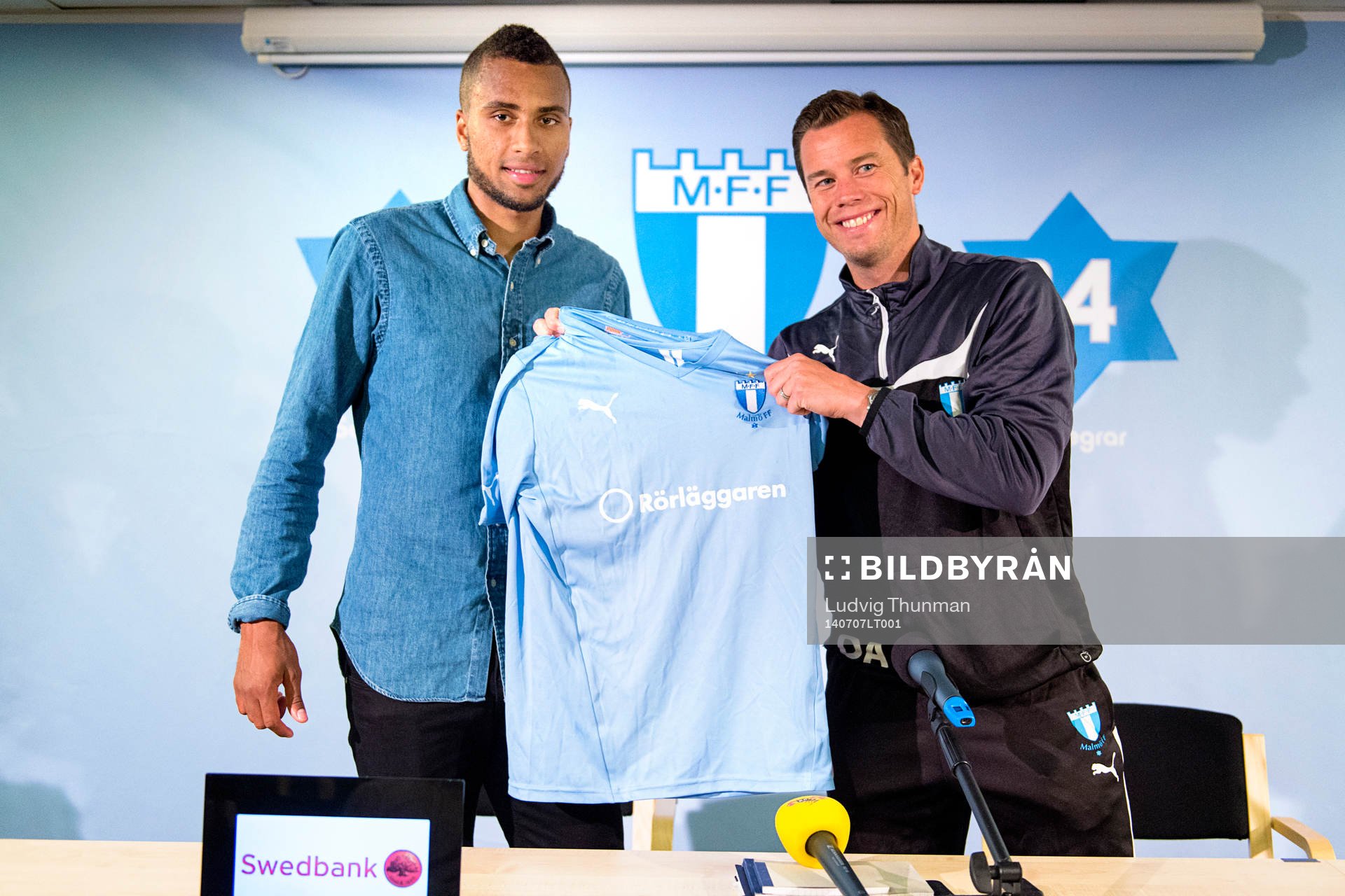 Malmös sportchef Daniel Andersson räcker över en matchtröja till Isaac Kiese Thelin under en presskonferens där Isaac Kiese Thelin presenteras som ny spelare i Malmö FF den 7 juli 2014 i Malmö.