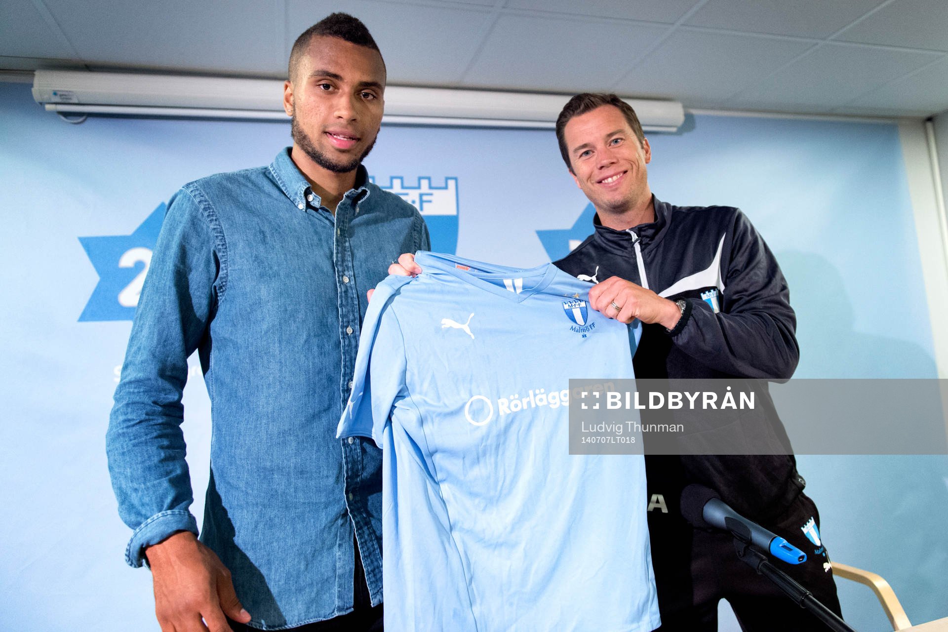 Malmös sportchef Daniel Andersson räcker över en matchtröja till Isaac Kiese Thelin under en presskonferens där Isaac Kiese Thelin presenteras som ny spelare i Malmö FF den 7 juli 2014 i Malmö.