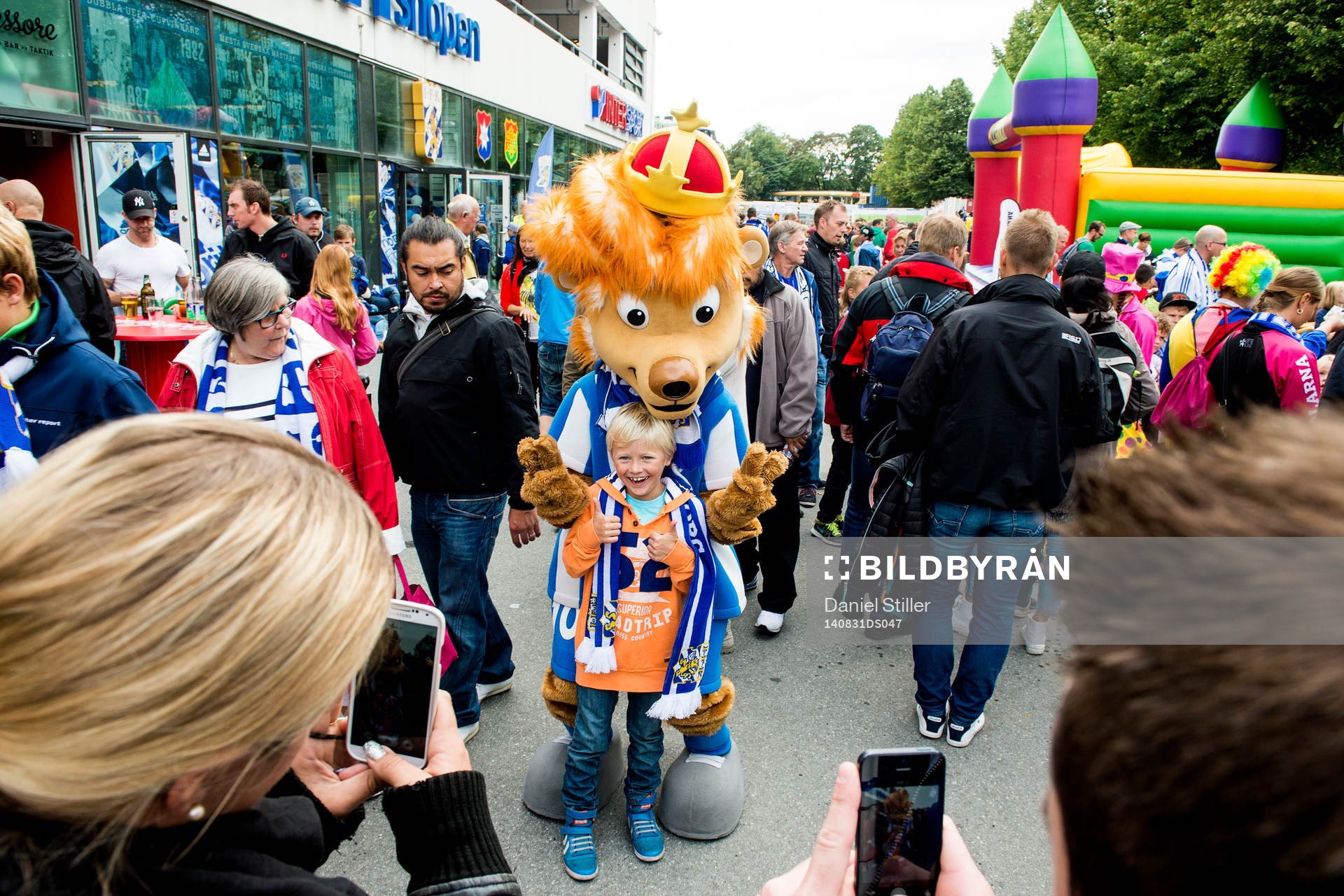 Maskoten Leo med en ung supporter innan fotbollsmatchen i