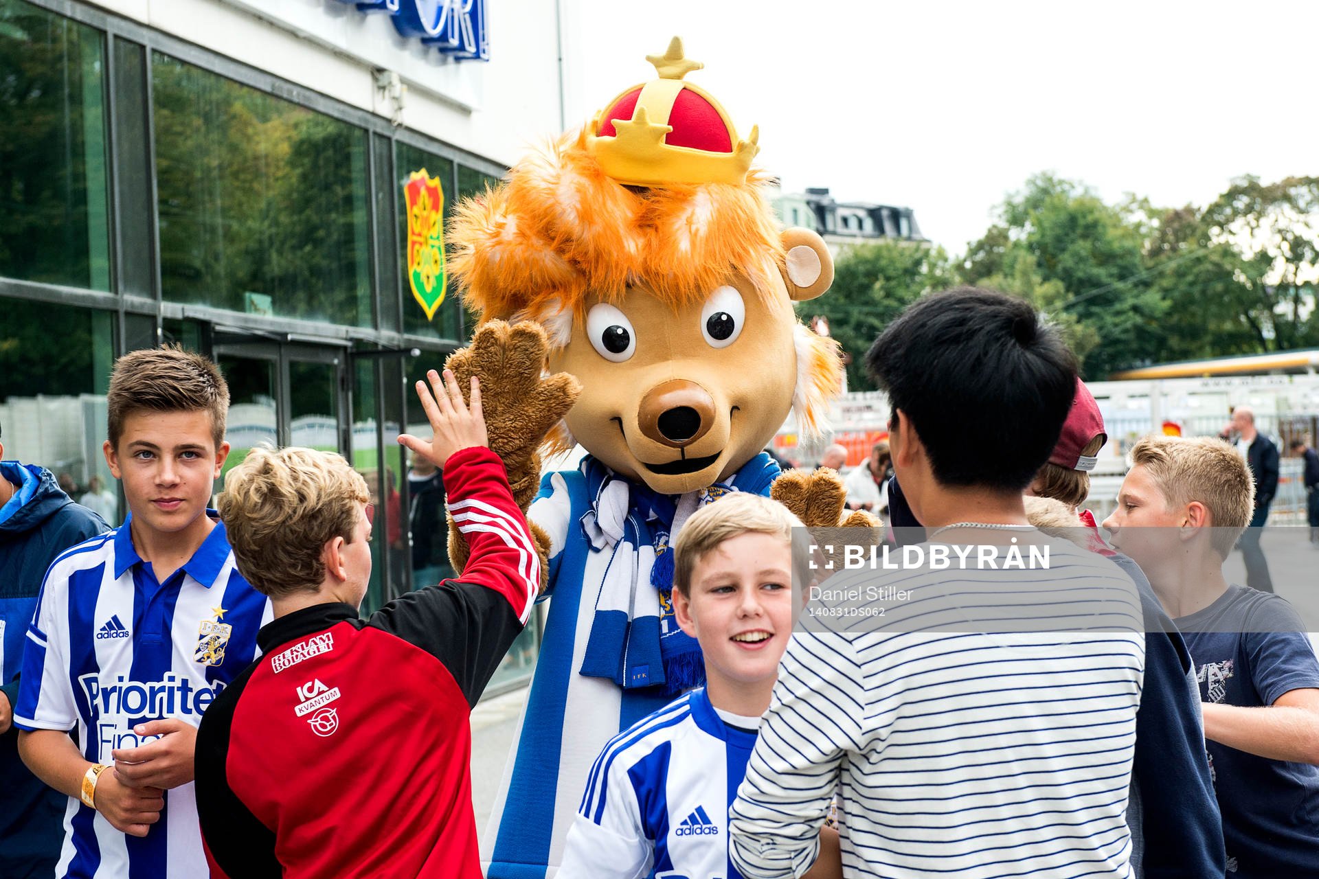 Unga supportrar med maskoten Leo innan fotbollsmatchen i