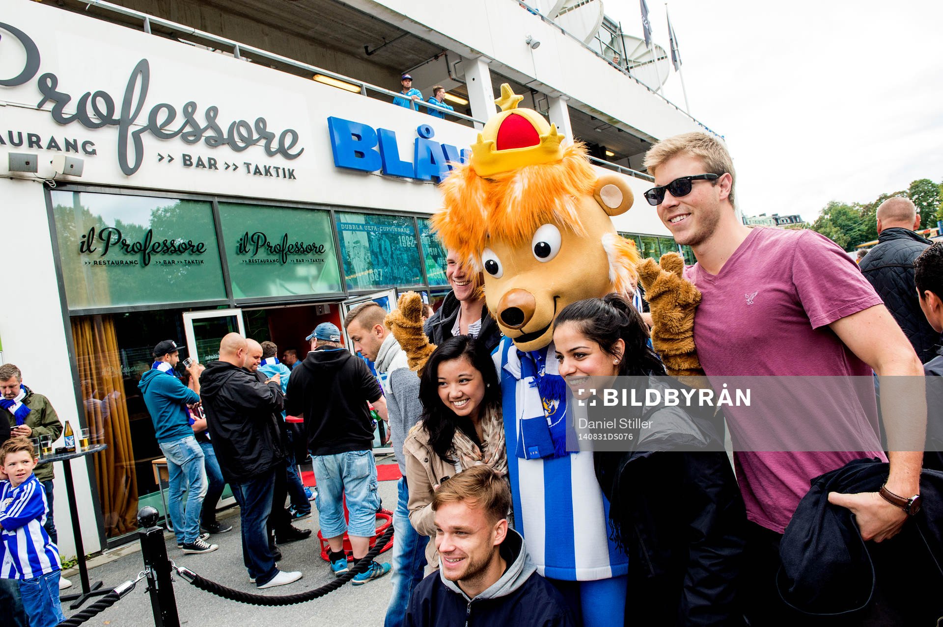 Maskoten Leo med supportrar innan fotbollsmatchen i