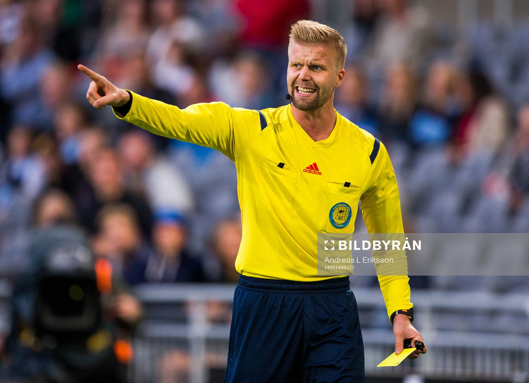 Domare Glenn Nyberg håller i ett gult kort