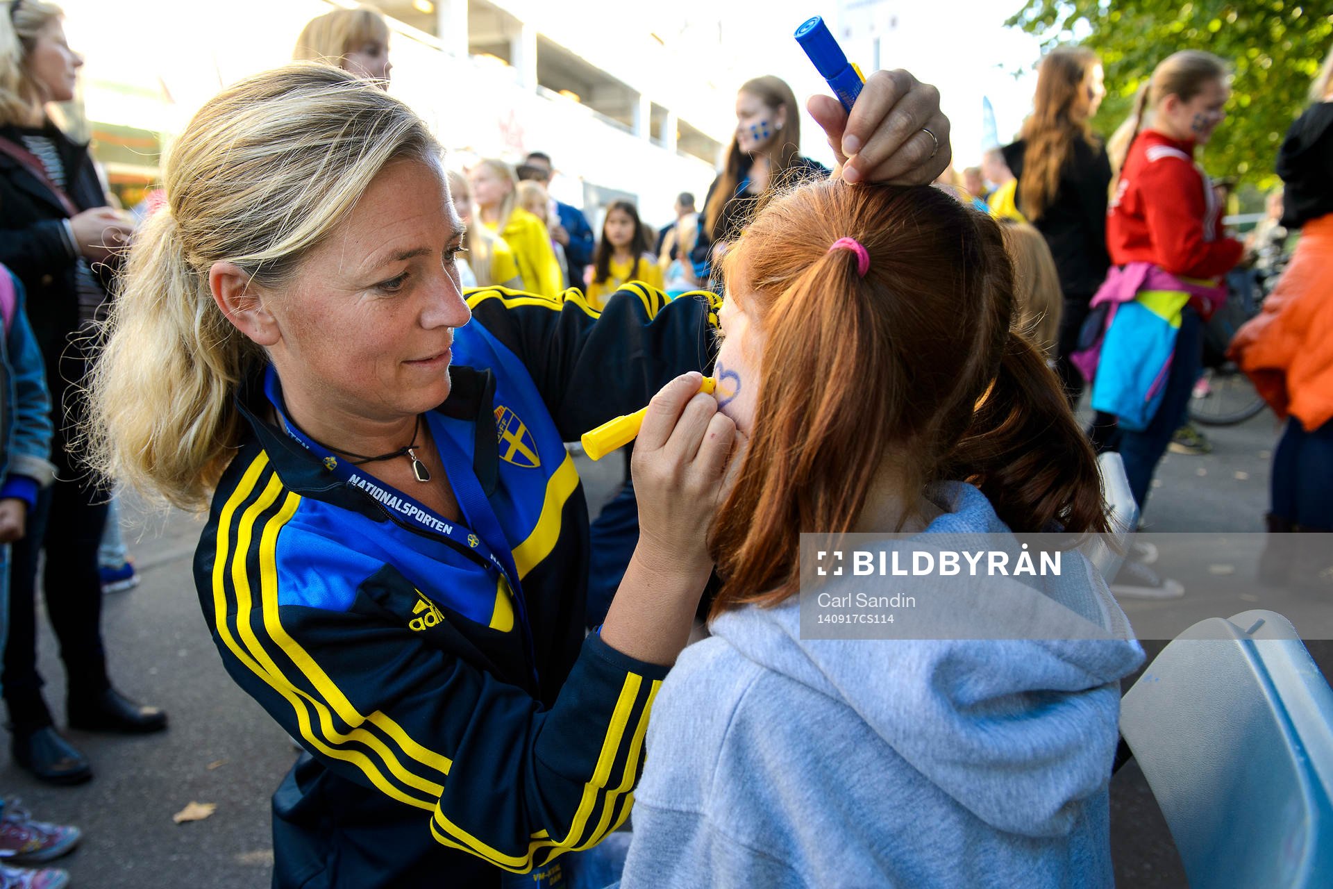 En tjej får ansiktet målat innan fotbollsmatchen i