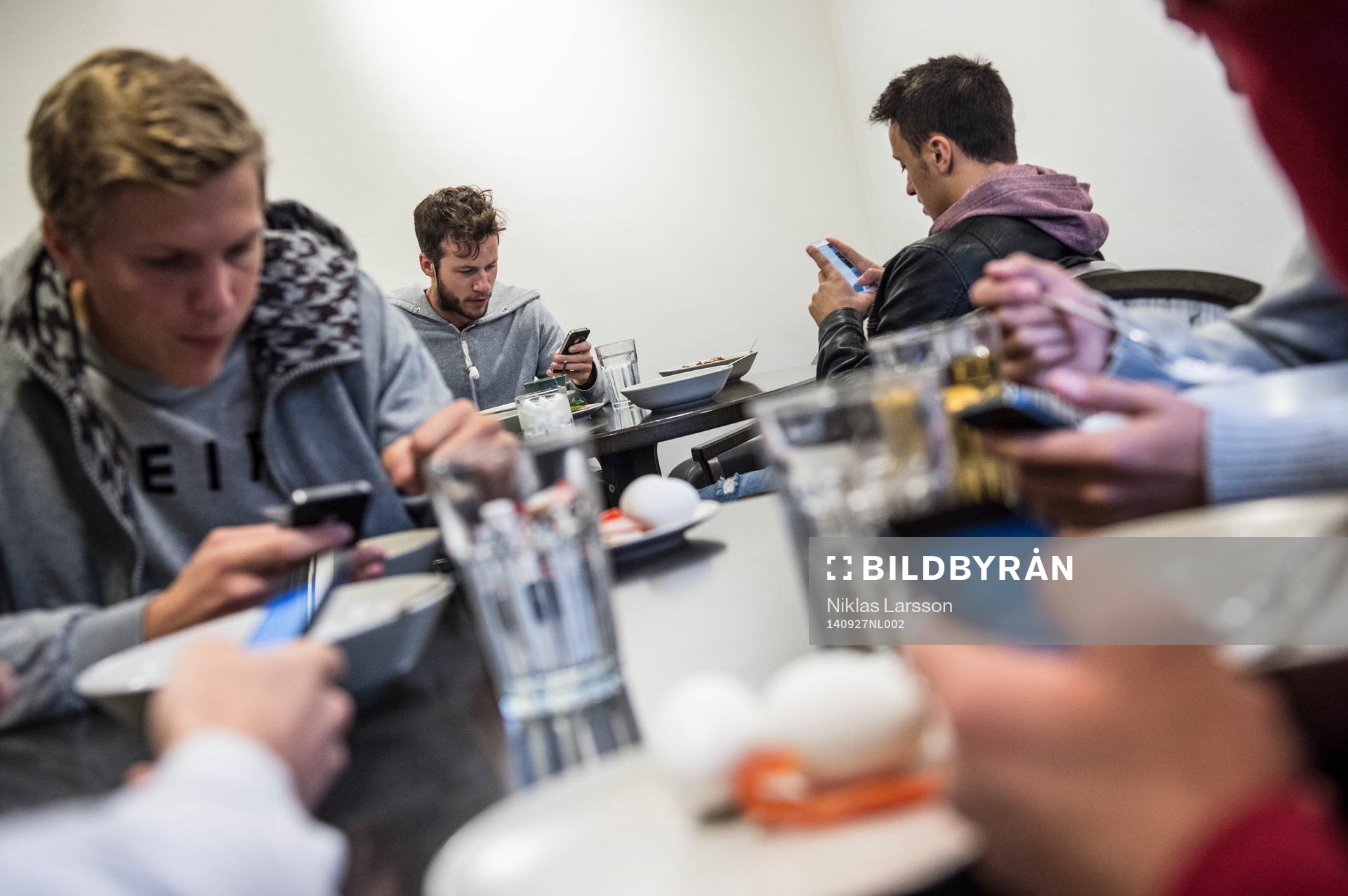 Robert Lundström, Adam Chenouffi och Joakim Nilsson tittar på sina telefoner under en frukost den 27 september 2014 i Sundsvall.