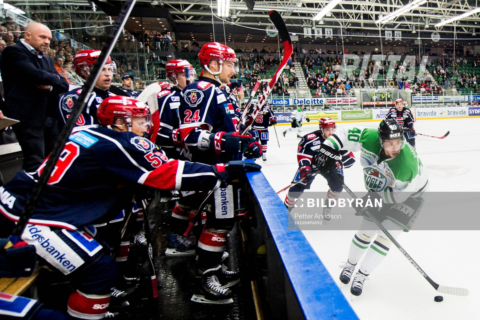 Rögles Jesper Jensen med pucken framför Södertäljes bås